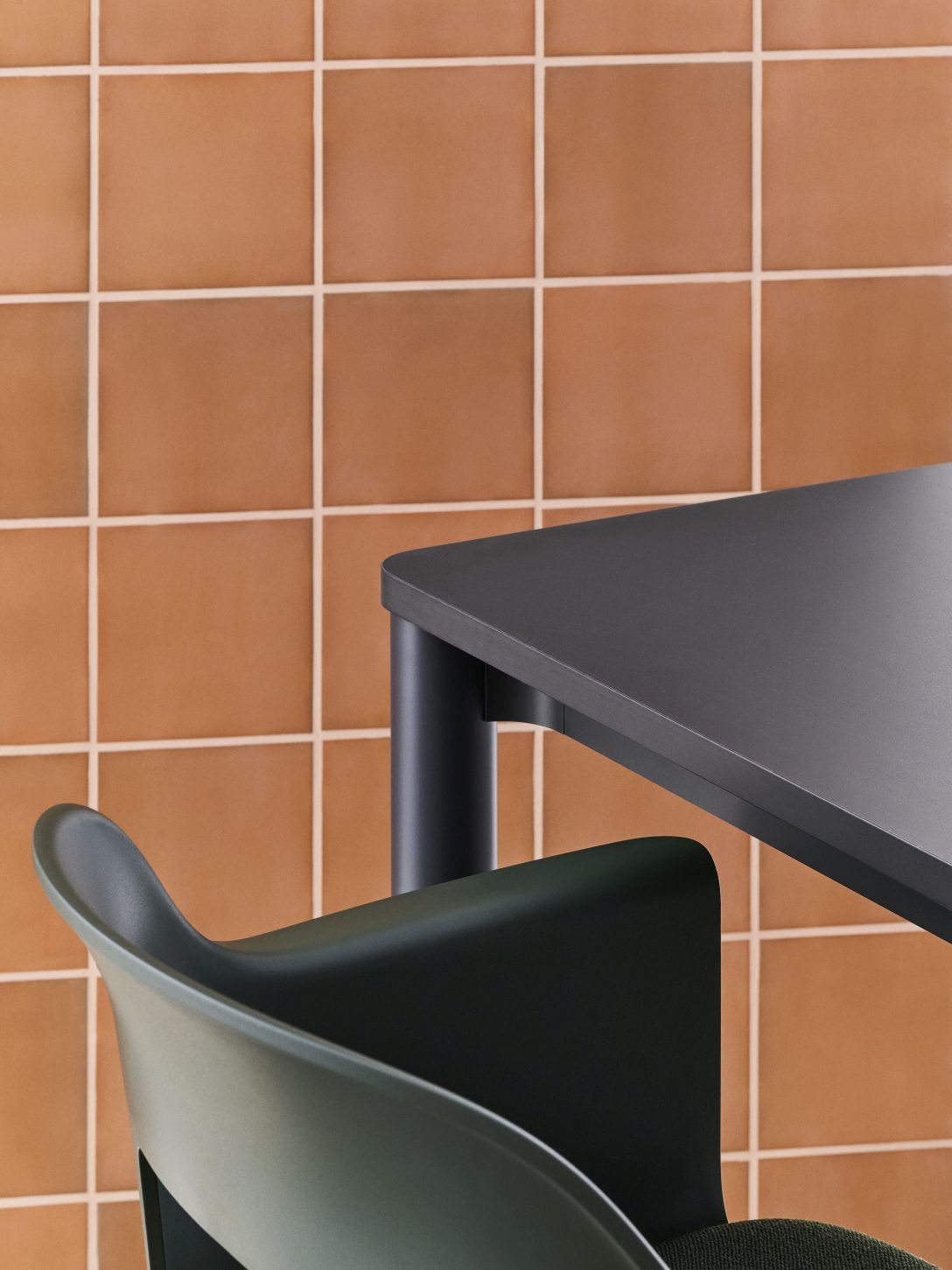 Detailaufnahme vom Hay Annex Table Esstisch in Anthrazit mit Stuhl vor einer Wand mit Terrakotta-Fliesen.