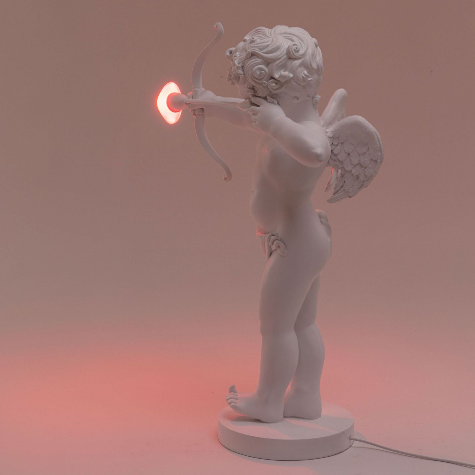 Cupid Lampe von Seletti: Skulptur eines weißen Amor mit Pfeil und Bogen als Tischleuchte.