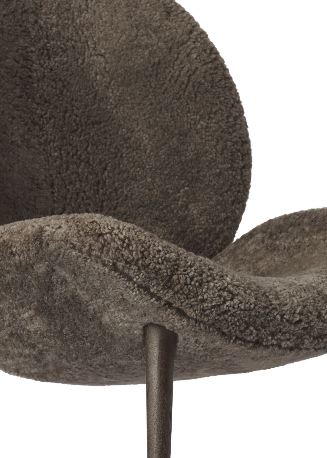 Detailaufnahme des Vipp Lodge Loungestuhls mit braunem, flauschigem Schaffellbezug und dunklen Holzbeinen.