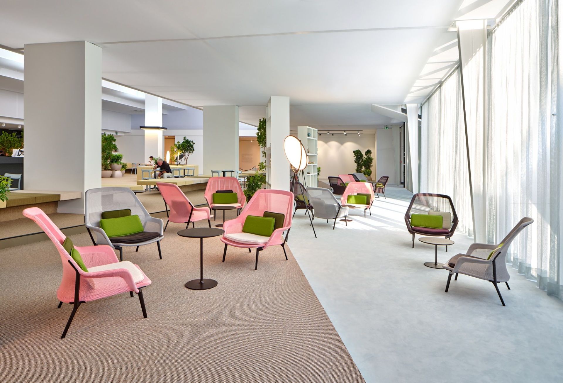 Helle, moderne Bürolounge mit mehreren Vitra Slow Chairs in Rosa, Grau und Braun mit Kissen.