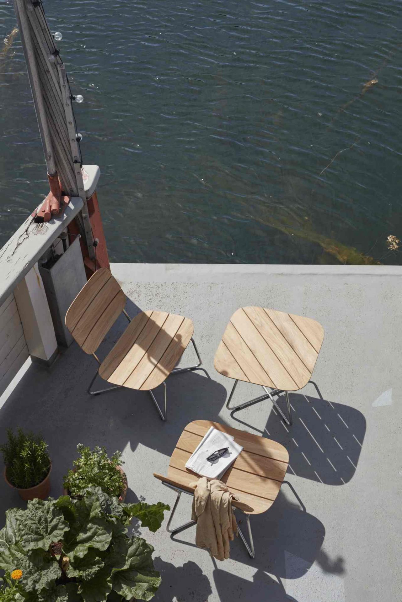 Lilium Lounge Chair von Skagerak: Outdoor Stuhl aus Teakholz mit Stahlgestell auf Terrasse.