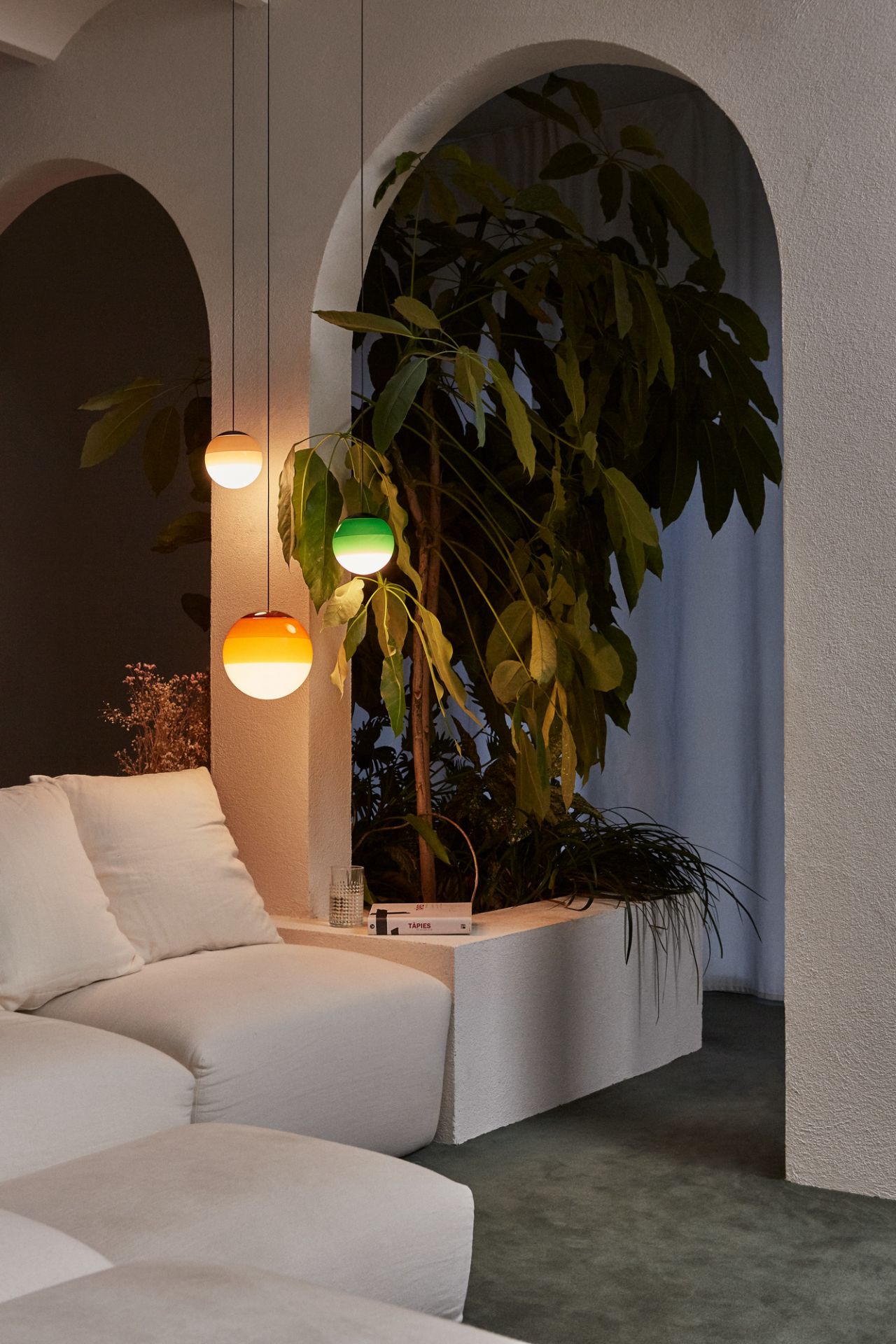 Nahaufnahme von drei Dipping Light Pendelleuchten von Marset in Bernstein, Grün und Weiß.