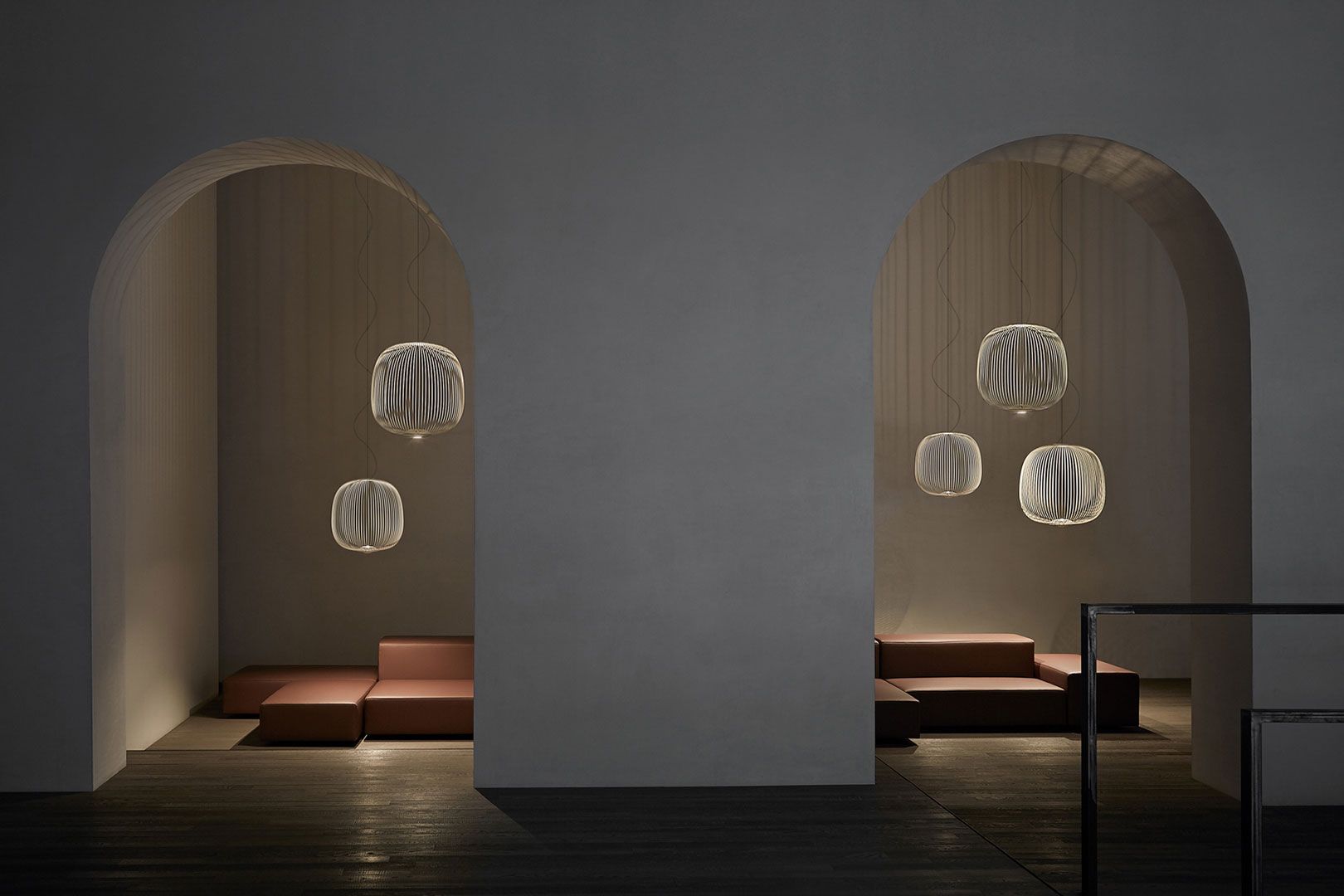 Mehrere Foscarini Spokes Pendelleuchten in Schwarz hängen in einem modernen Raum.