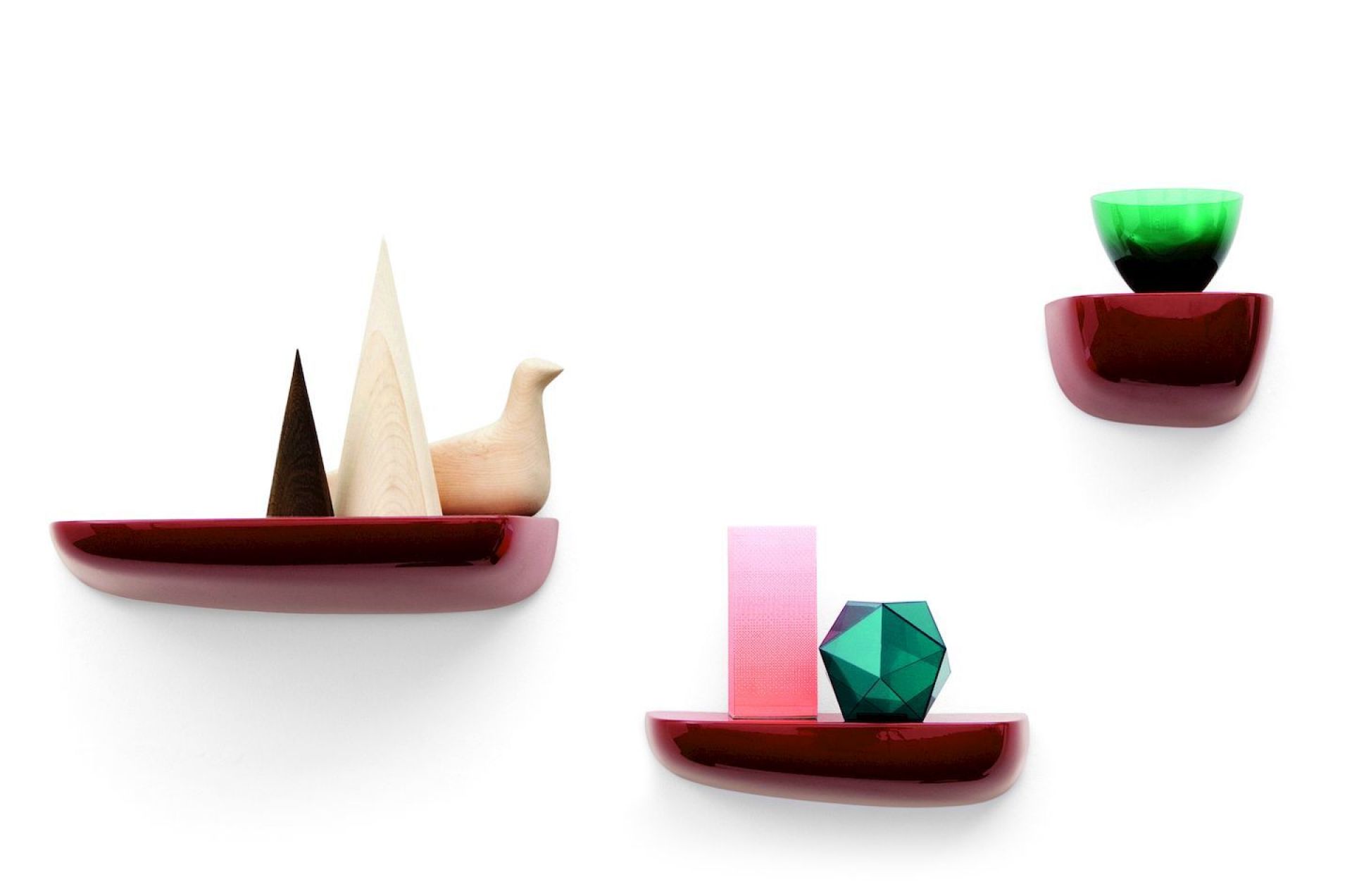 Drei rote Vitra Corniches Wandboards mit Deko-Objekten an einer weißen Wand.