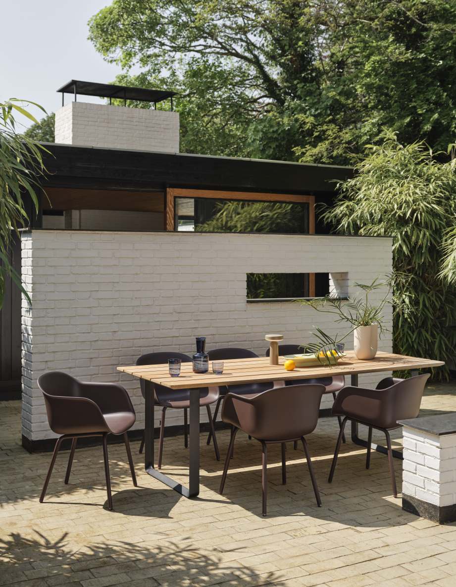 Muuto Fiber Armchair: Brauner Outdoor Armlehnstuhl am Gartentisch für entspanntes Verweilen im Freien.