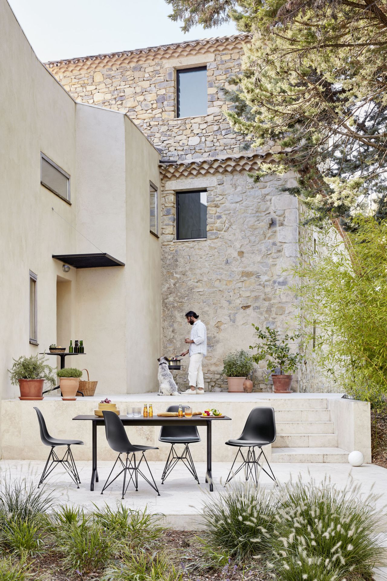 Schwarzer Eames Plastic Side Chair DSR von Vitra am Esstisch im Außenbereich. Designklassiker mit Stahlgestell.