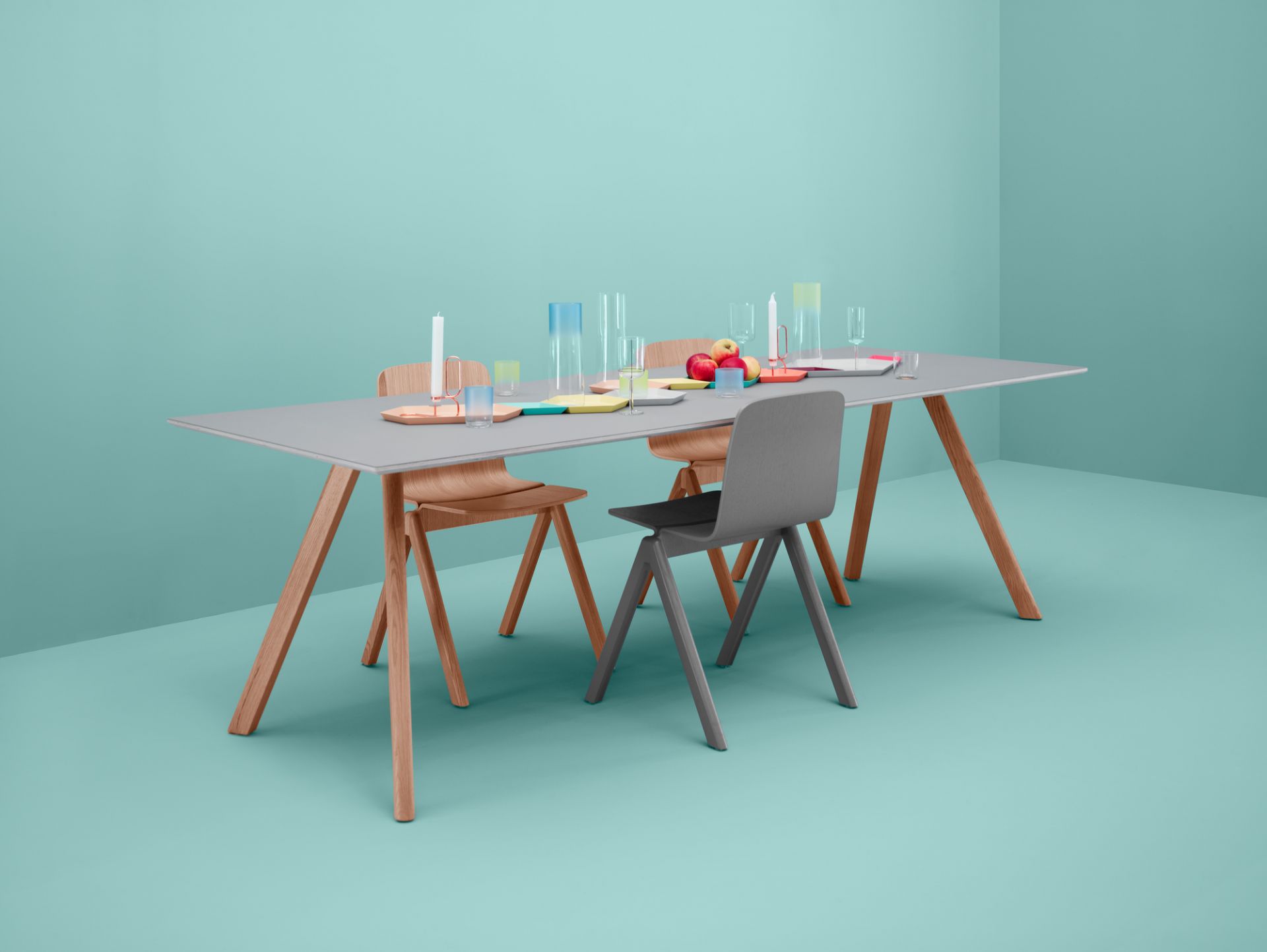 Heller Copenhague Table CPH 30 Tisch von Hay mit Stühlen und Tischdeko vor mintgrünem Hintergrund.