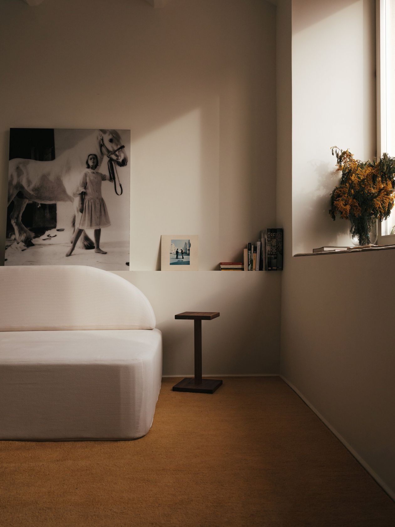 Santa & Cole Peana Molina Beistelltisch aus dunklem Holz neben einem weißen Sofa in minimalistischem Interieur.