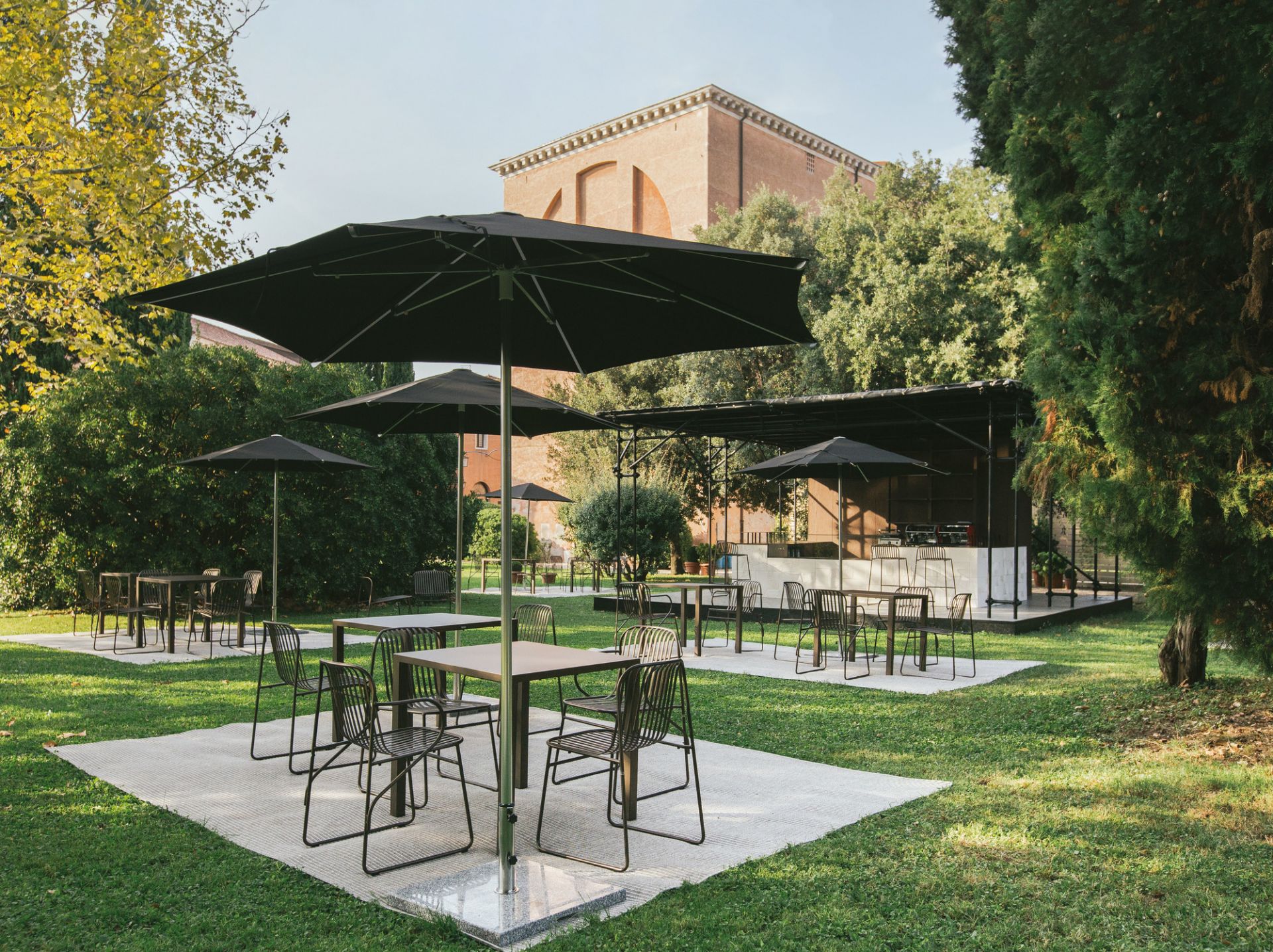 Riviera Stuhl Antikes Eisen von Emu, Gartenmöbel-Set mit Tischen und Stühlen auf Rasenfläche.
