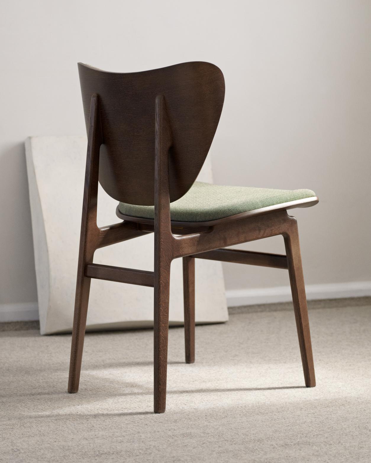 Rückansicht des NORR11 Elephant Dining Chair Stuhls mit grüner Sitzpolsterung und dunklem Holzrahmen.