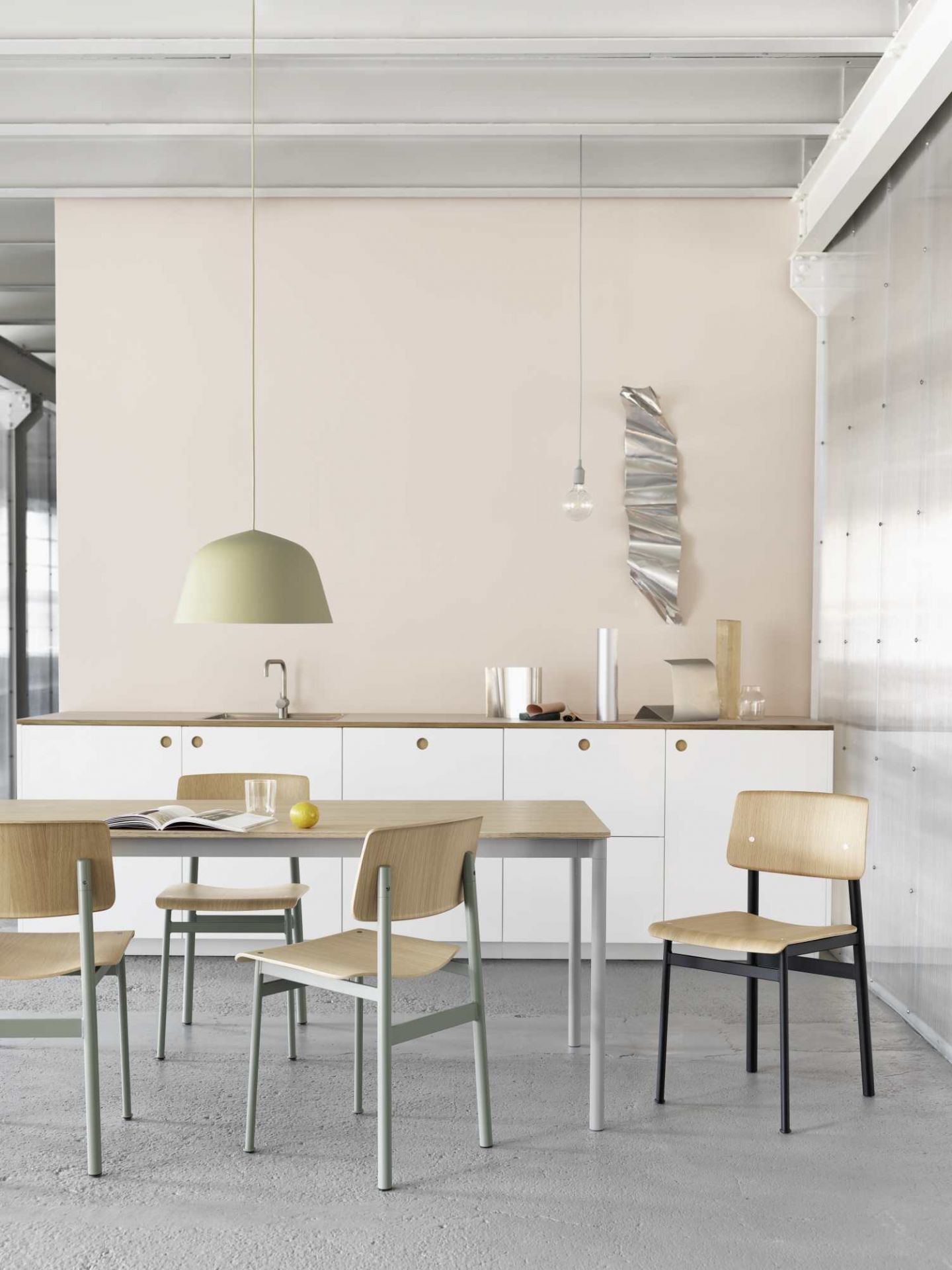 Helle Küche mit Esstisch und Muuto Ambit Pendelleuchte 55 in Olivgrün über dem Tisch.