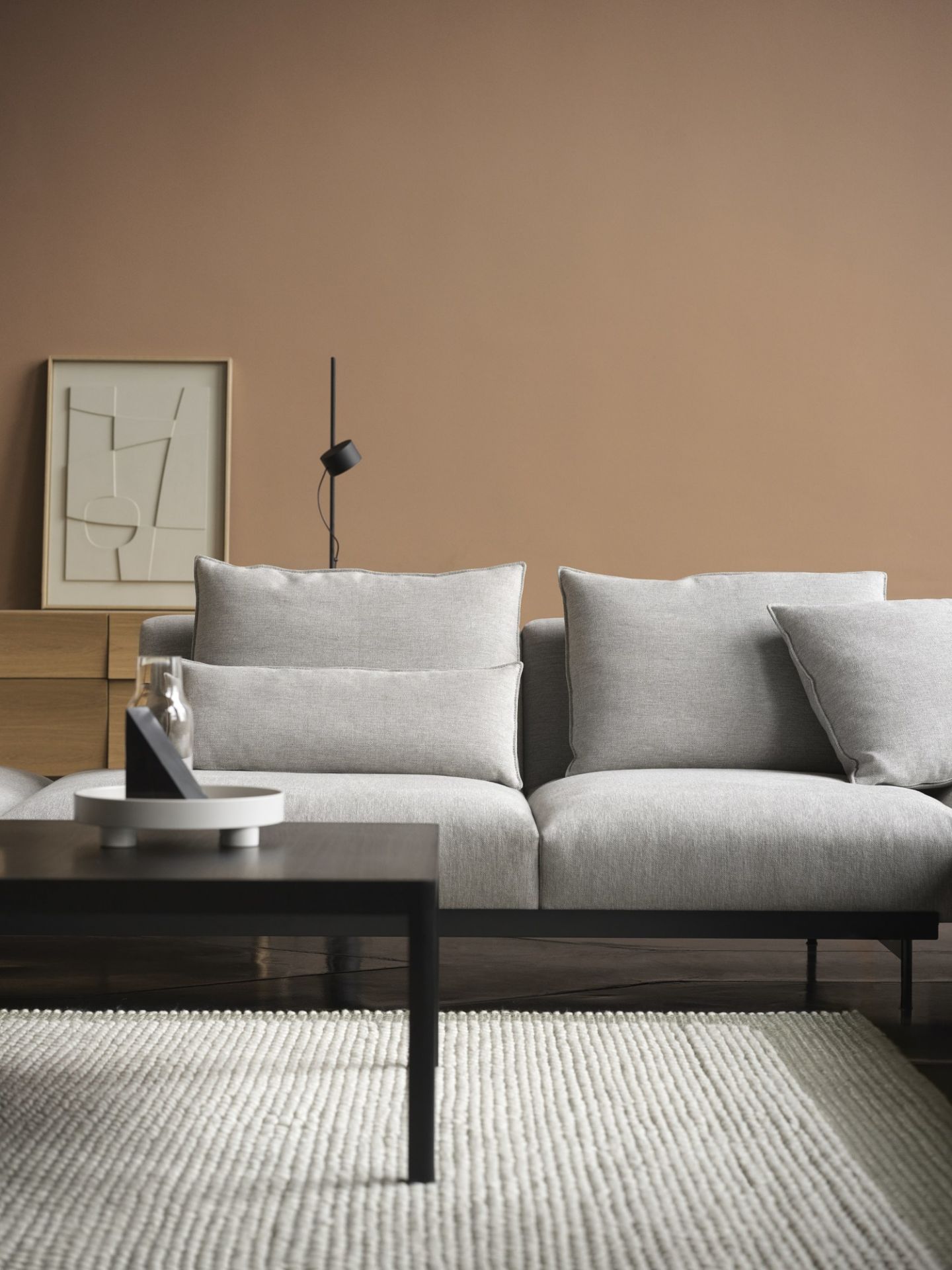 Wohnzimmer-Szene mit grauem Sofa, Couchtisch, Teppich und Muuto Sideboard im Hintergrund.