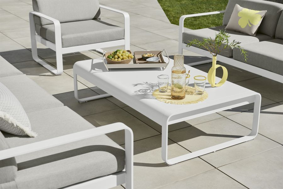 Weißer Bellevie Outdoor Tisch von Fermob mit Getränken und Snacks auf einer Terrasse.
