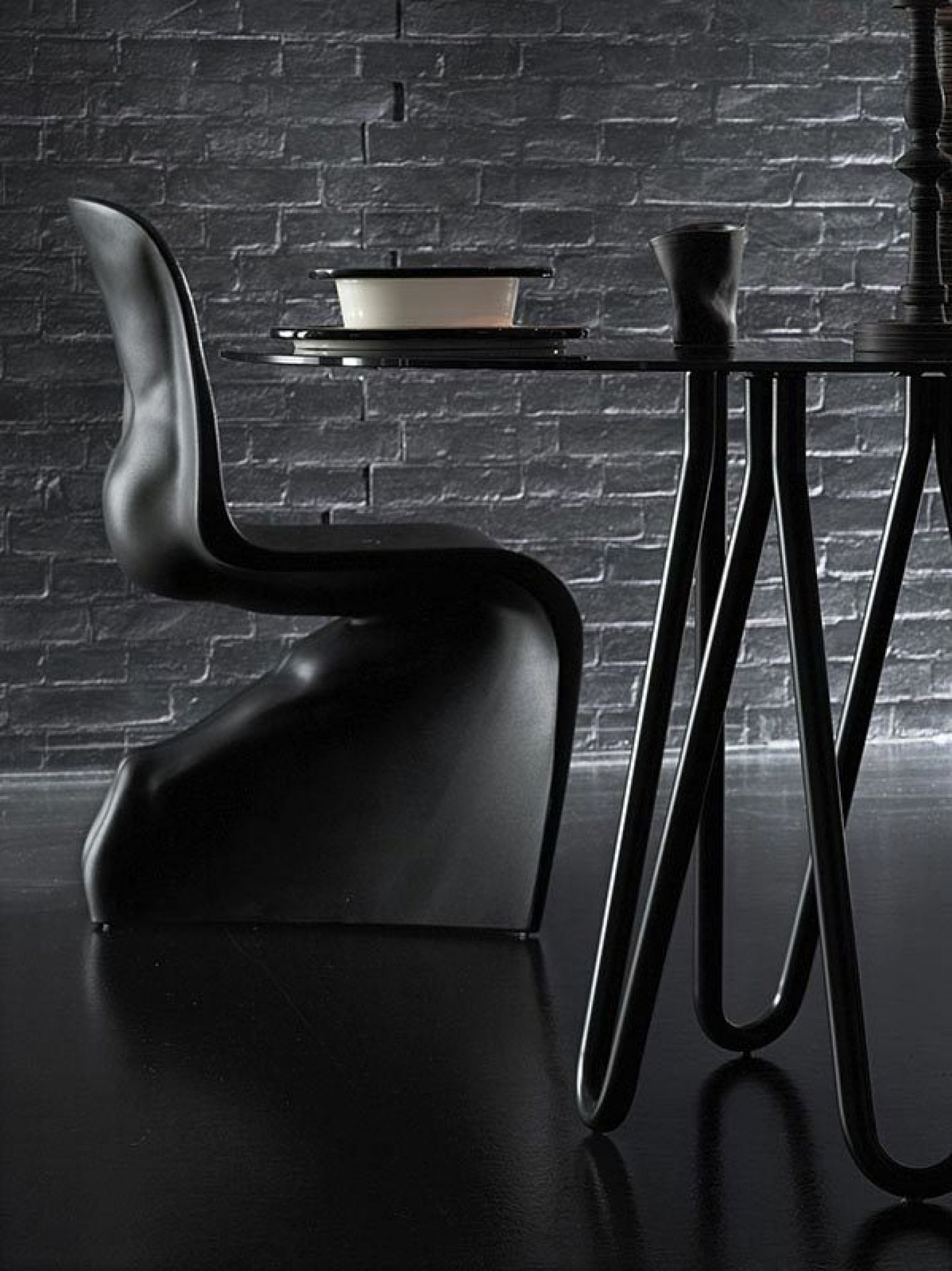 Schwarzer Him Stuhl von Casamania Horm neben einem Esstisch mit Geschirr. Designermöbel.