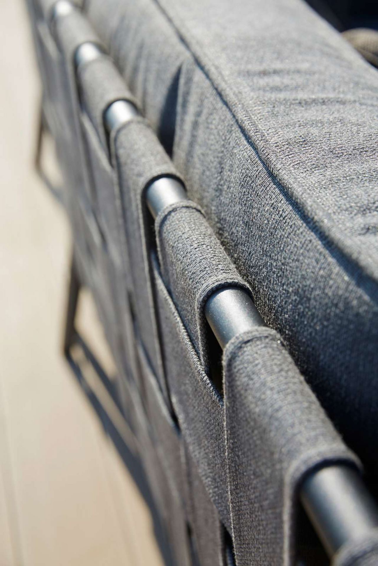 Detailaufnahme des Cane-Line Conic Outdoor Modulsofas: Graues Textilgewebe und silberne Metallrohre.
