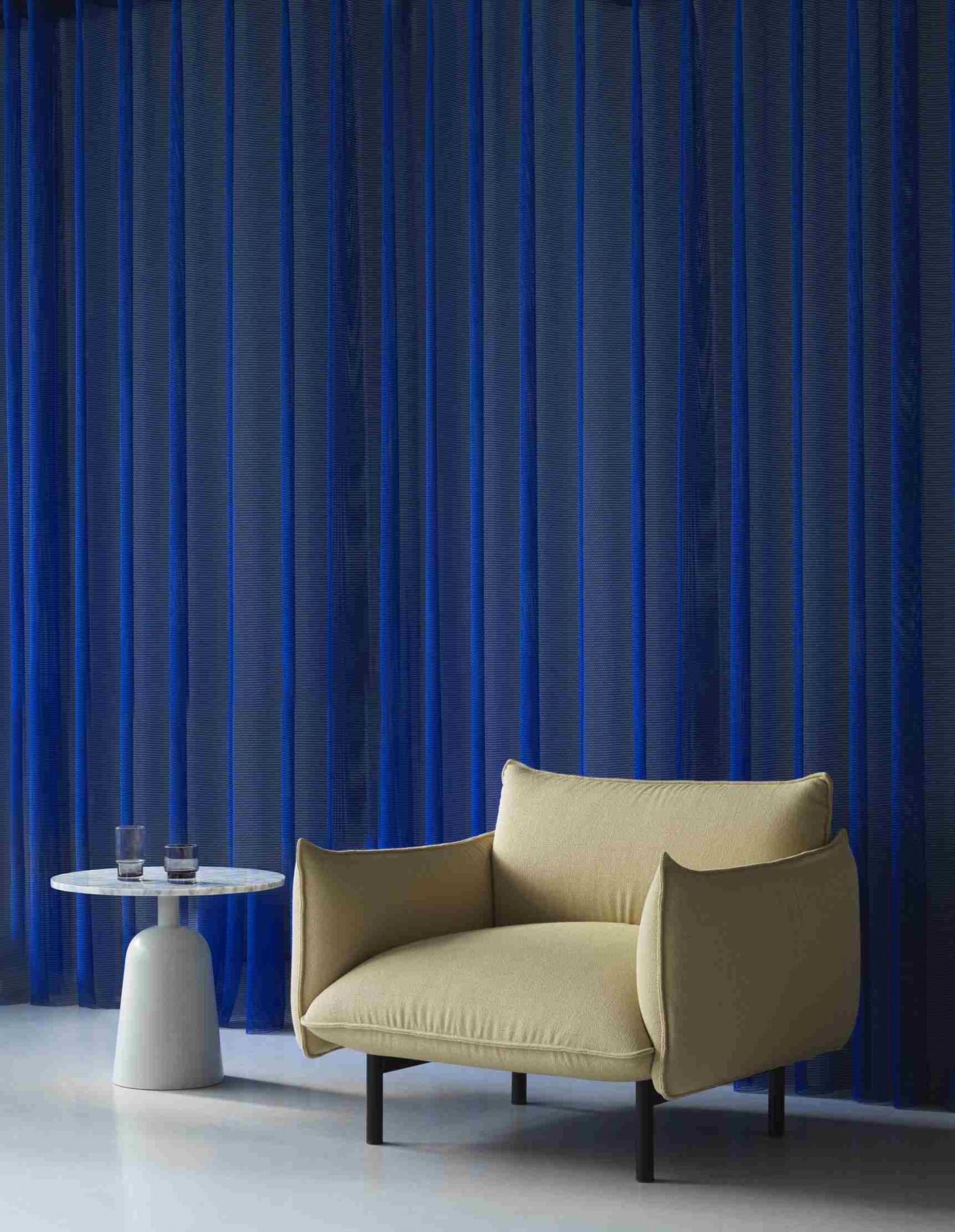 Ark Lounge Chair Sessel von Normann Copenhagen in Beige mit Beistelltisch und blauen Vorhängen.
