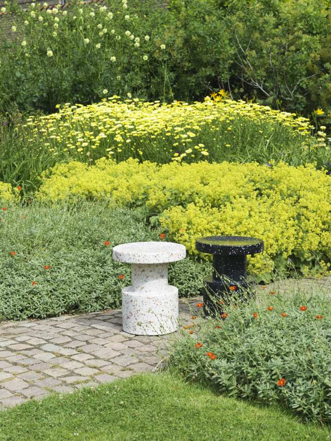 Normann Copenhagen Bit Stool Hocker, weiß und schwarz, im Garten auf Pflastersteinen.