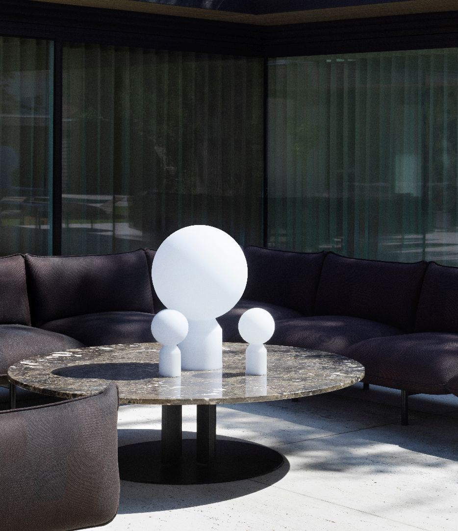 Normann Copenhagen Yo Lamp Small Tischleuchte als Akzentbeleuchtung auf einem runden Marmortisch mit Sofa.