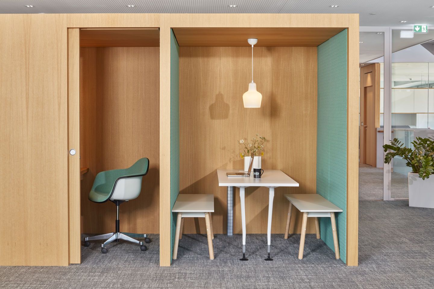Büro-Szene mit Eames Plastic Arm Chair in Grün, Schreibtisch und Sitzbank in Holzkabine.