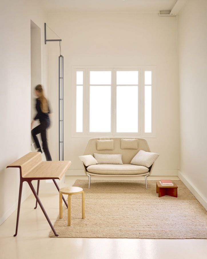Beige Vitra Slow Sofa aus Stoff in minimalistischem Raum mit Teppich, Schreibtisch und Fenster.
