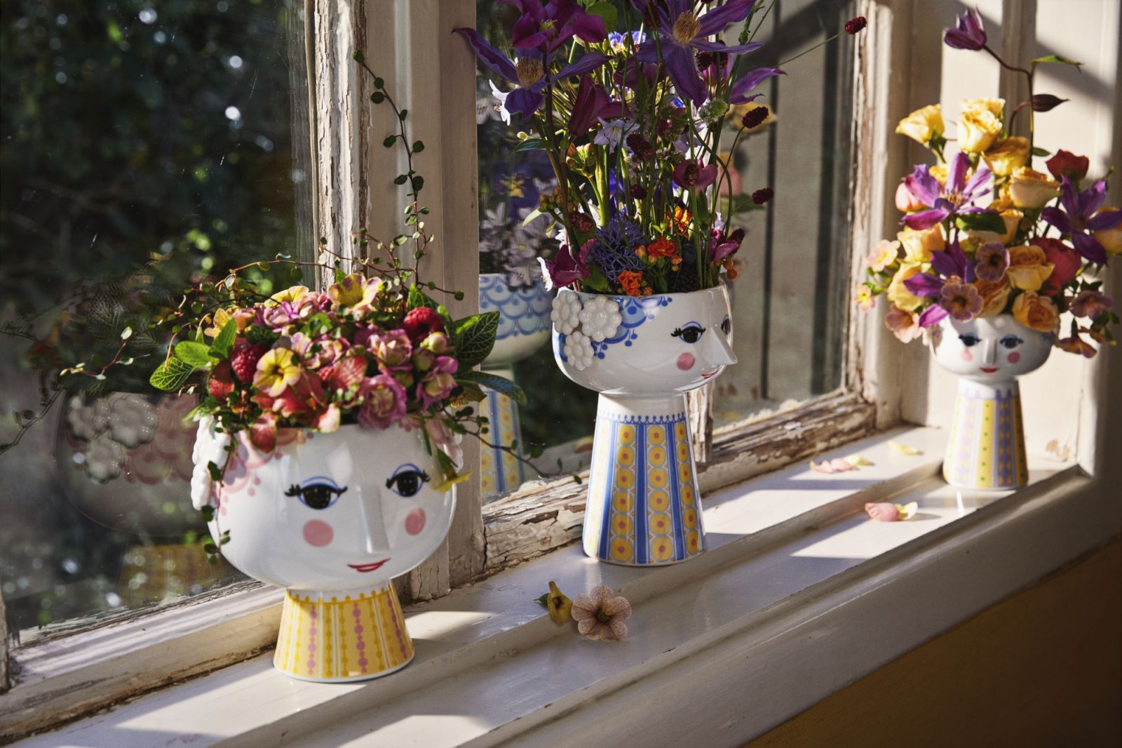 Drei Bjørn Wiinblad Eva Vasen mit Blumen auf einer Fensterbank, lavendelfarbene Akzente. Keramikvase im Gesicht Design.