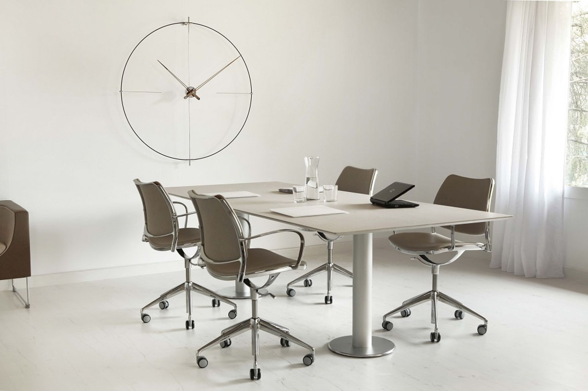 Minimalistische Bilbao Nomon Wanduhr in Schwarz-Schwarz über einem Konferenztisch in einem hellen Büro.