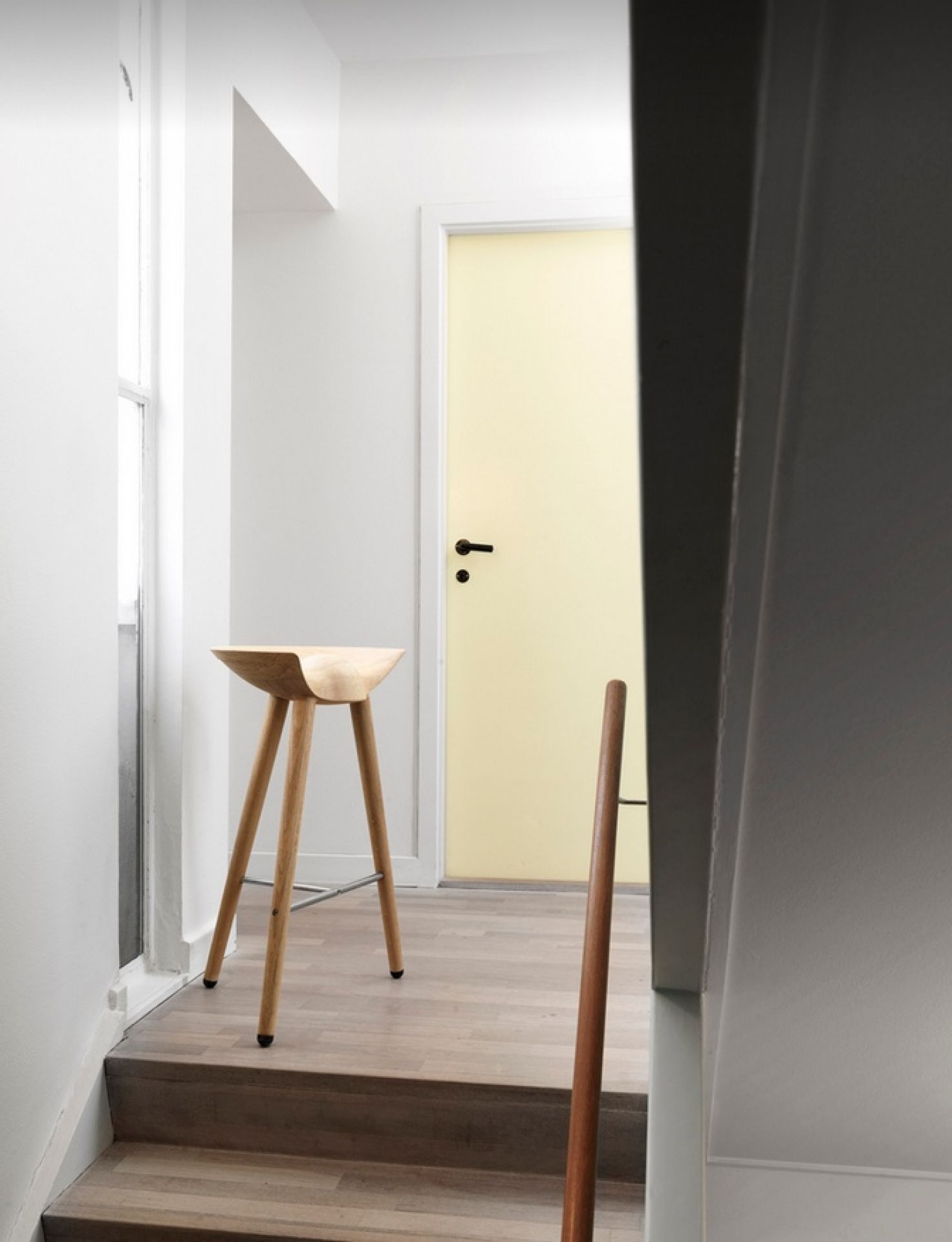 ML42 Barhocker Audo aus hellem Holz auf Treppe vor gelber Tür, minimalistisches Design.