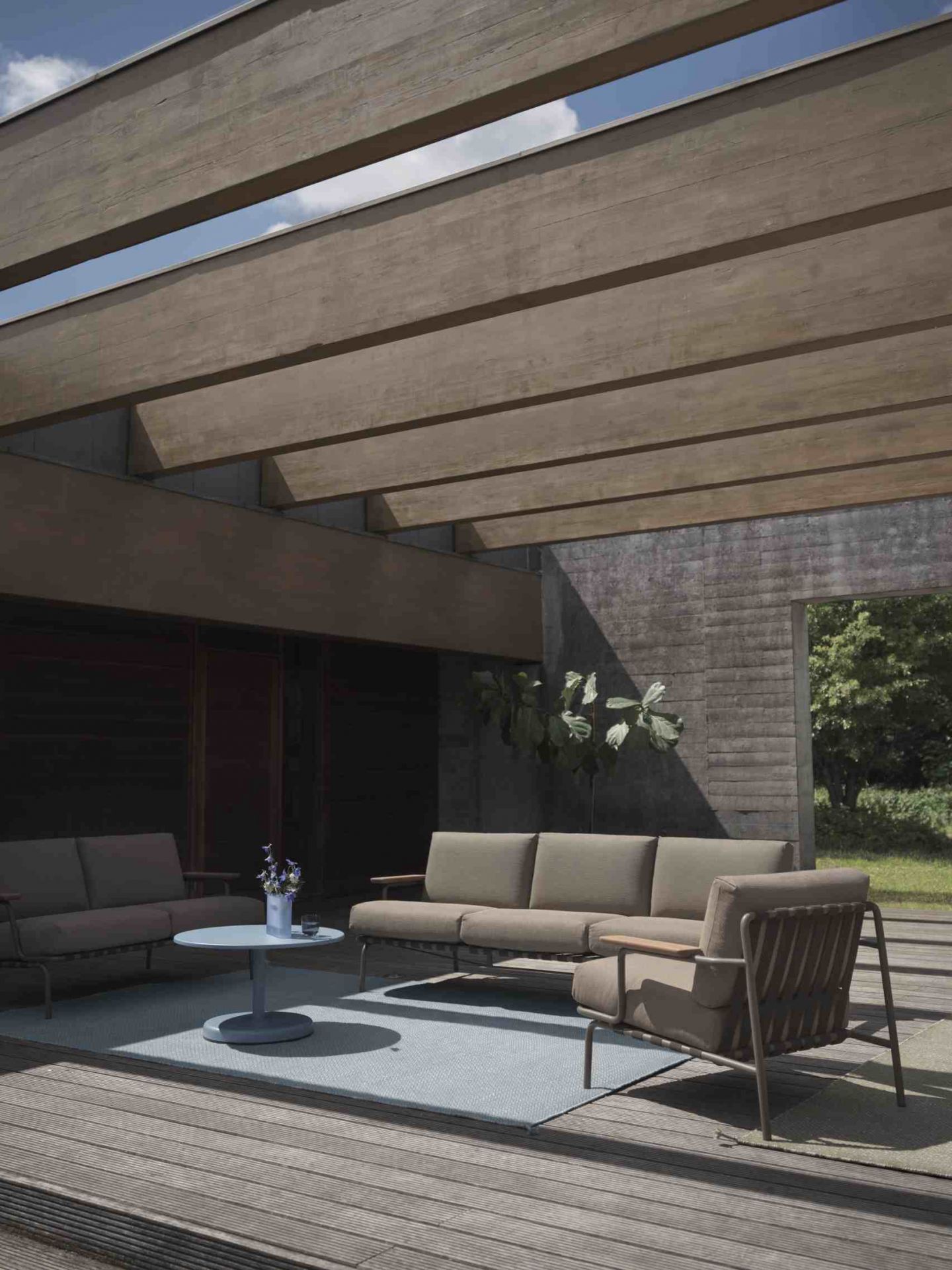Muuto Ply Rug aus recyceltem Polyester, hellblauer Outdoor Teppich auf Holzterrasse mit Gartenmöbeln.