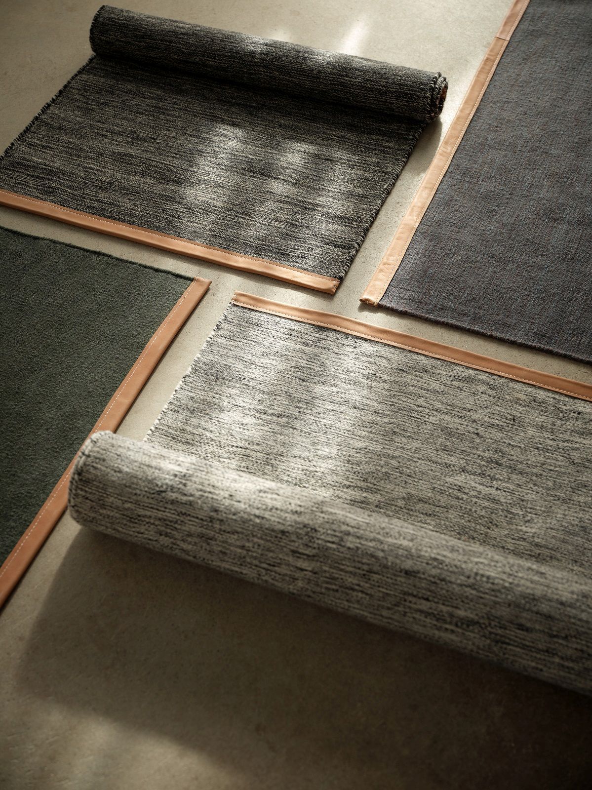 Mehrere Björk Teppiche von Design House Stockholm in Grau- und Grüntönen mit Lederdetails.