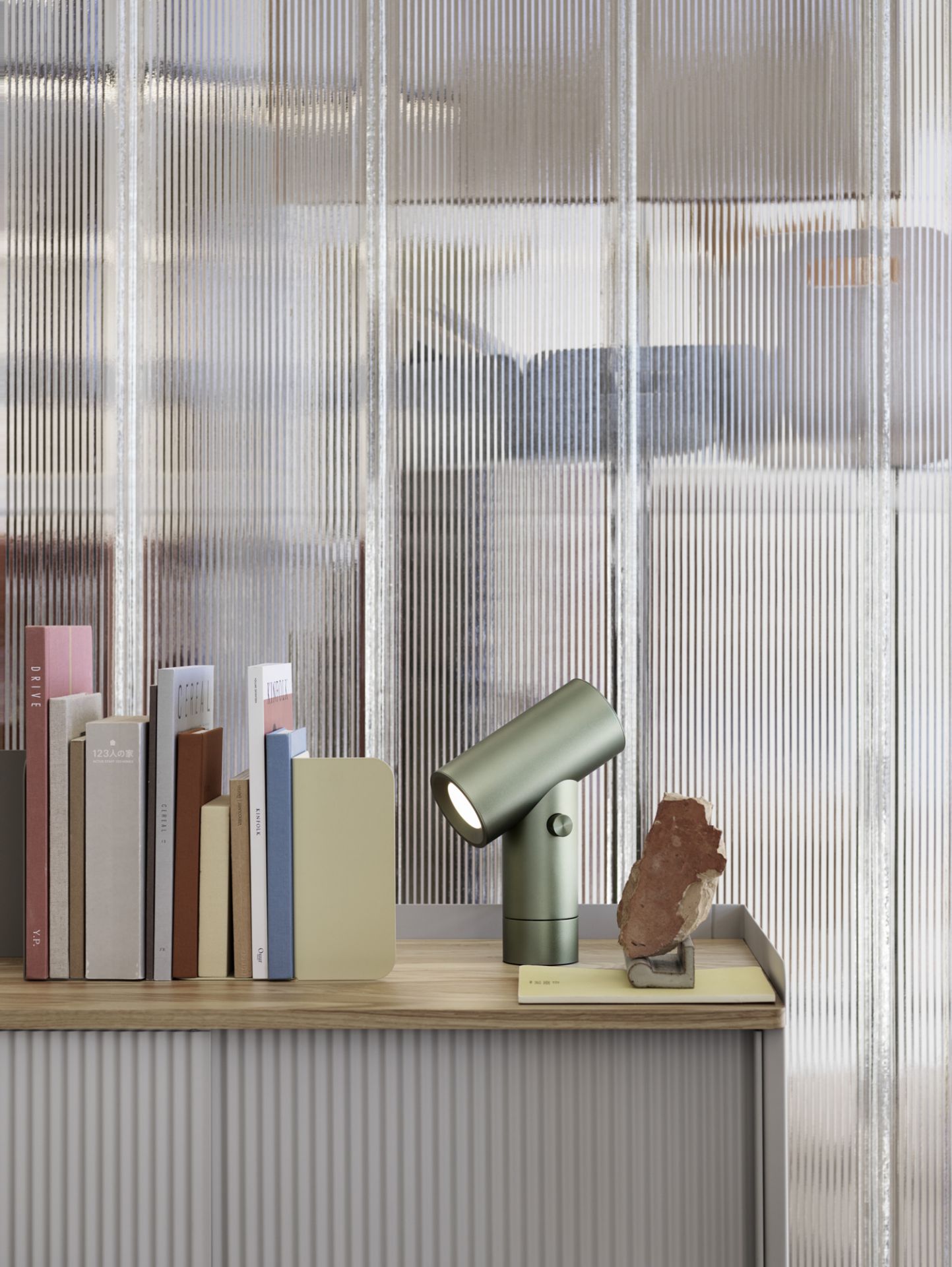 Nahaufnahme der grünen Muuto Beam Tischleuchte aus Aluminium auf einem Regal mit Büchern.