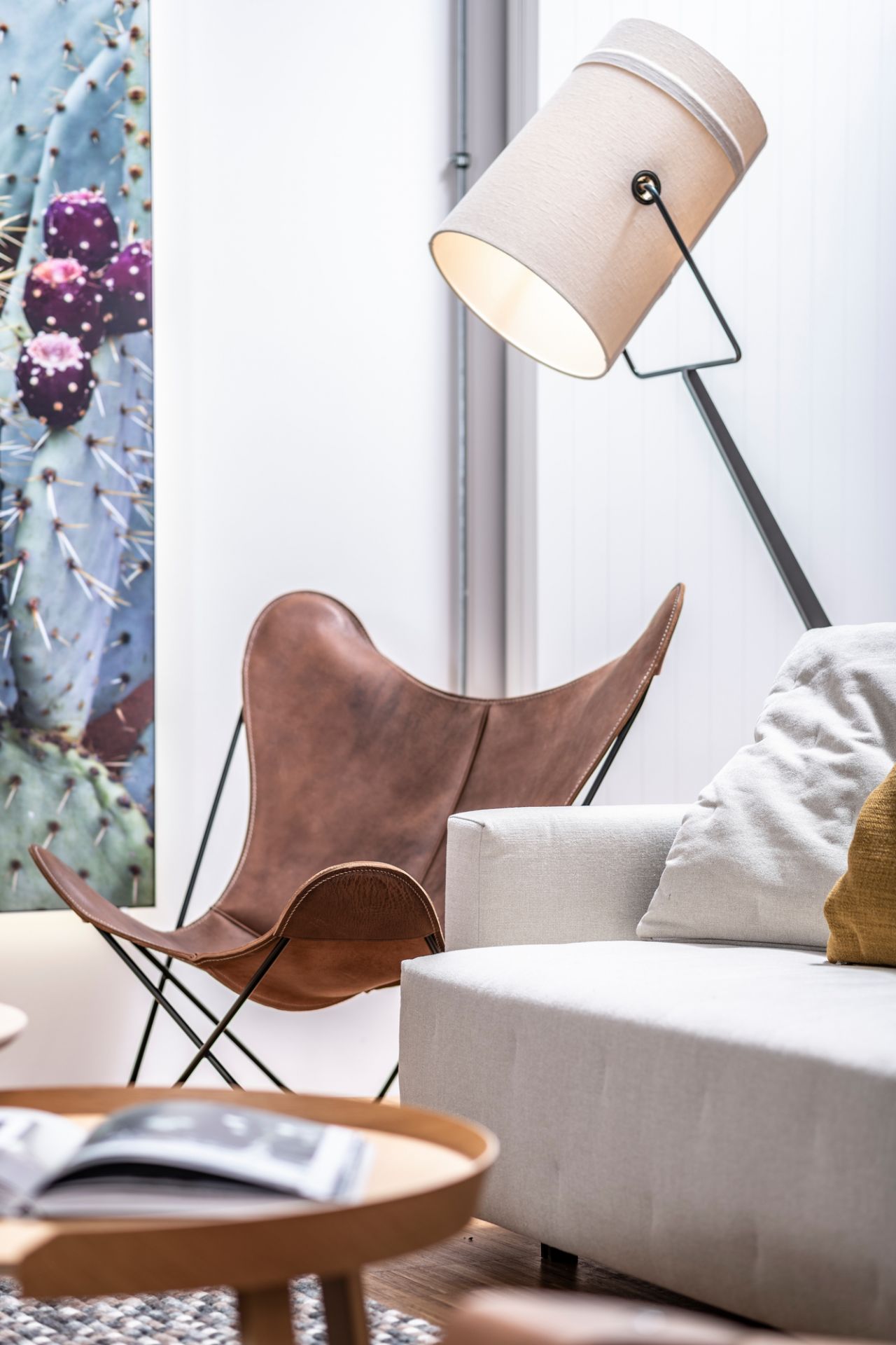 Muuto Around Coffee Table aus Eiche in einem Wohnzimmer mit Sessel, Sofa und Stehlampe.