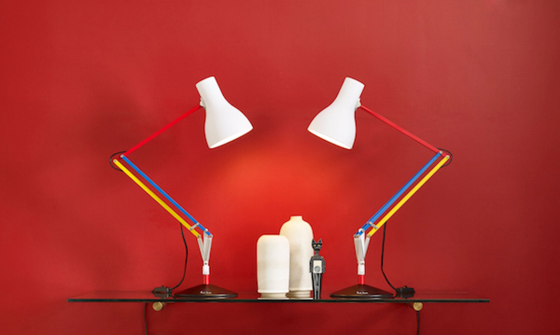 Zwei Anglepoise Type 75 Mini Paul Smith Edition Tischleuchten in Weiß, Rot, Gelb und Blau auf Glasregal.