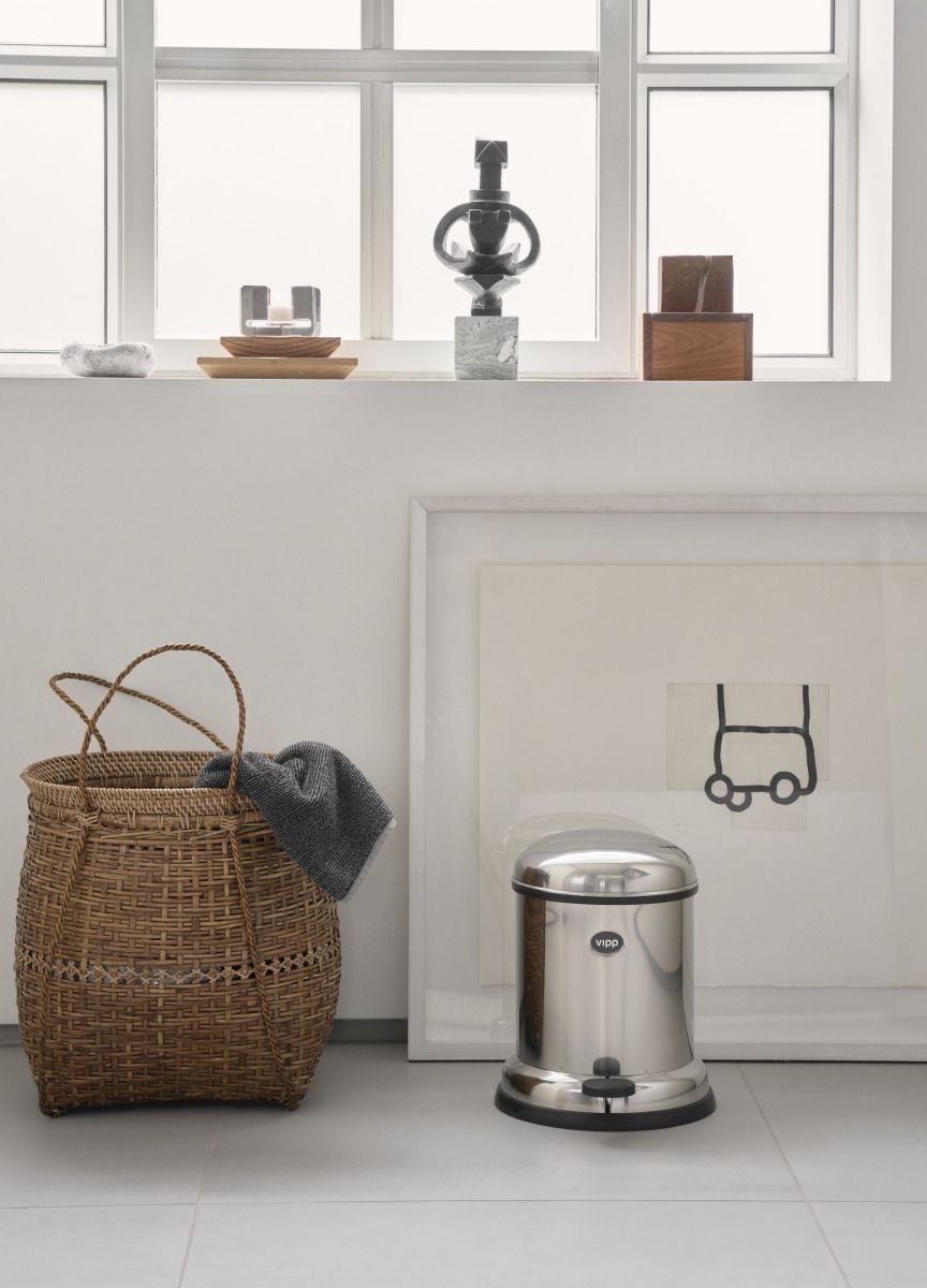 Vipp Treteimer 4L aus Edelstahl im Badezimmer, neben Korb und Kunstwerk.