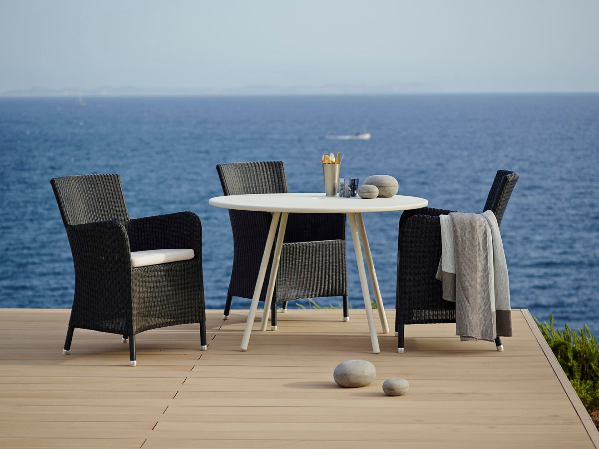 Hampsted Outdoor Sessel von Cane-Line mit Esstisch und Meerblick, moderne Gartenmöbel aus Rattan.