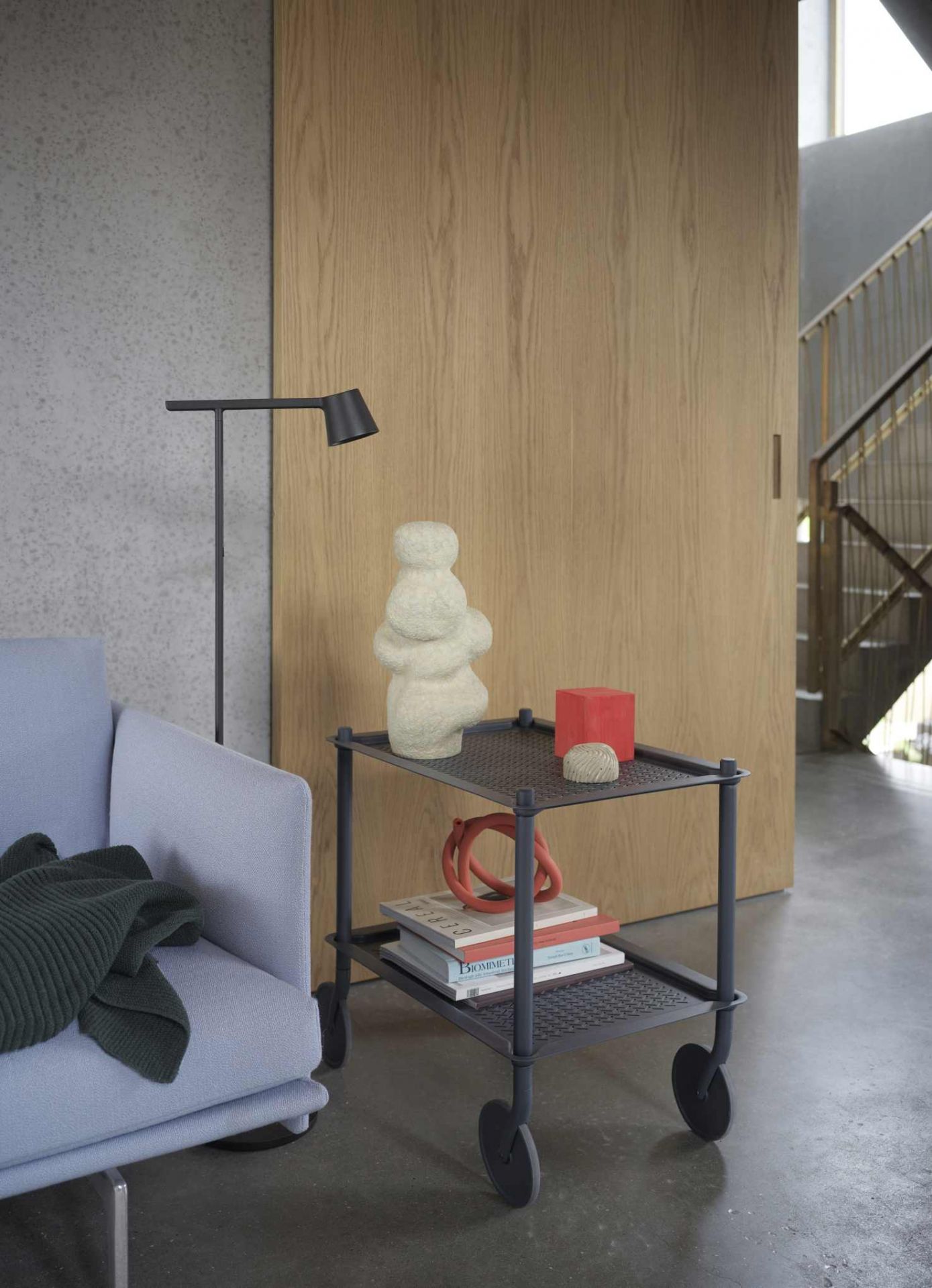 Muuto Flow Trolley Servierwagen in Grau mit zwei Ablageflächen, dekoriert mit Skulpturen und Büchern im Wohnzimmer.
