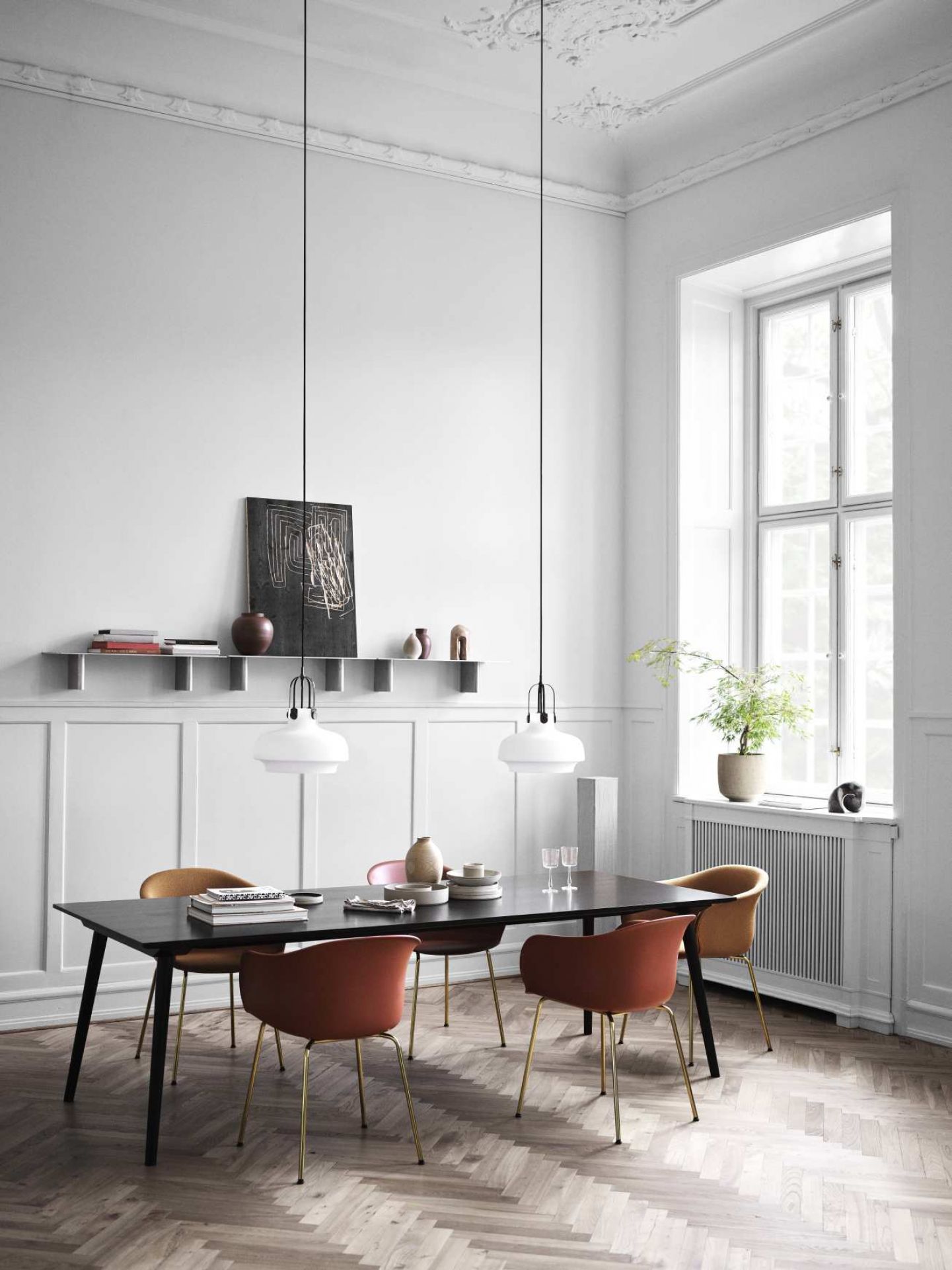AndTradition In Between Table SK5/SK6 Esstisch mit Stühlen und Pendelleuchten in einem hellen, modernen Esszimmer.