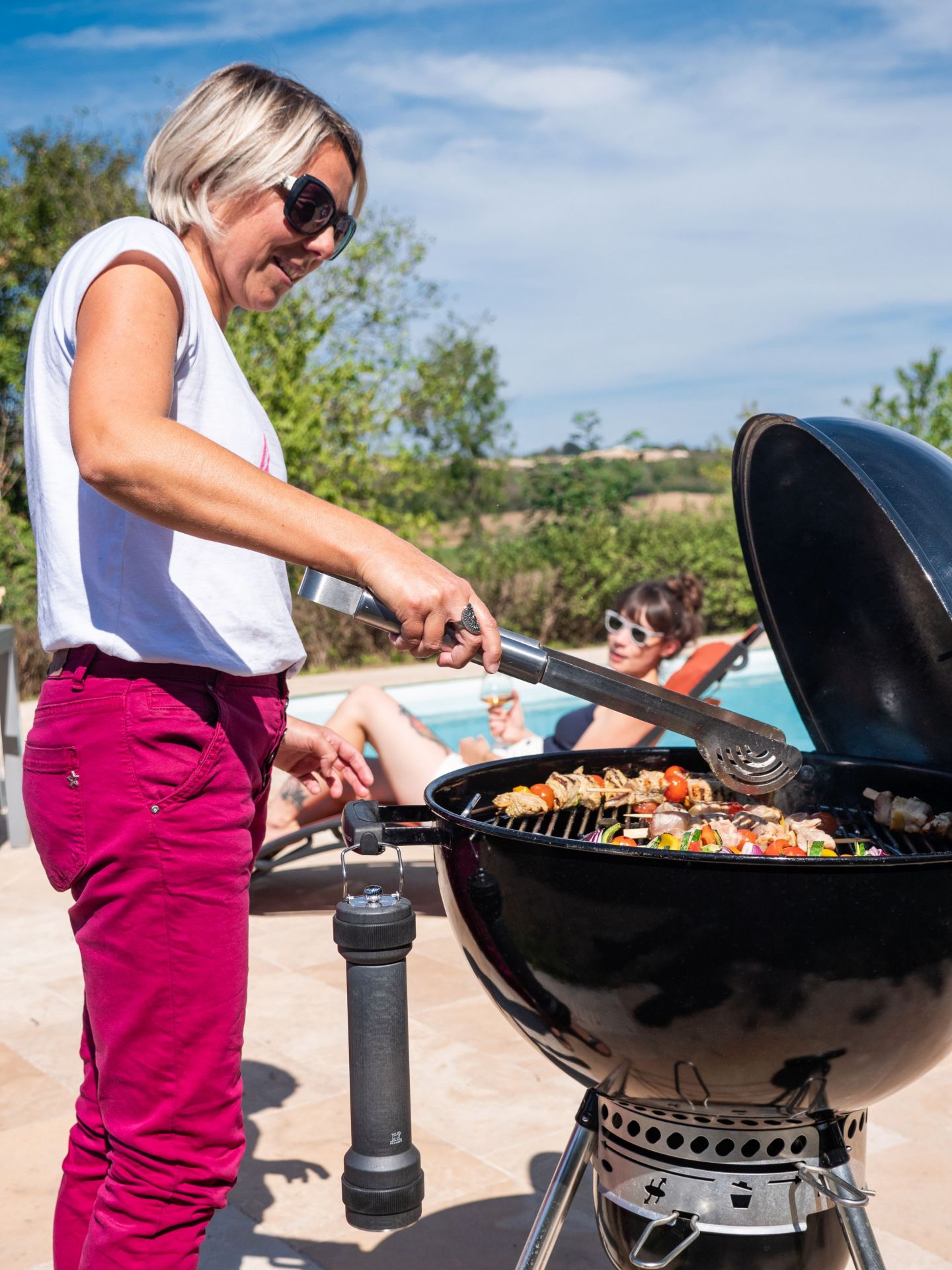 Frau grillt mit Peugeot BBQ Pfeffermühle im Freien, Grillspieße mit Gemüse und Fleisch auf dem Grill.