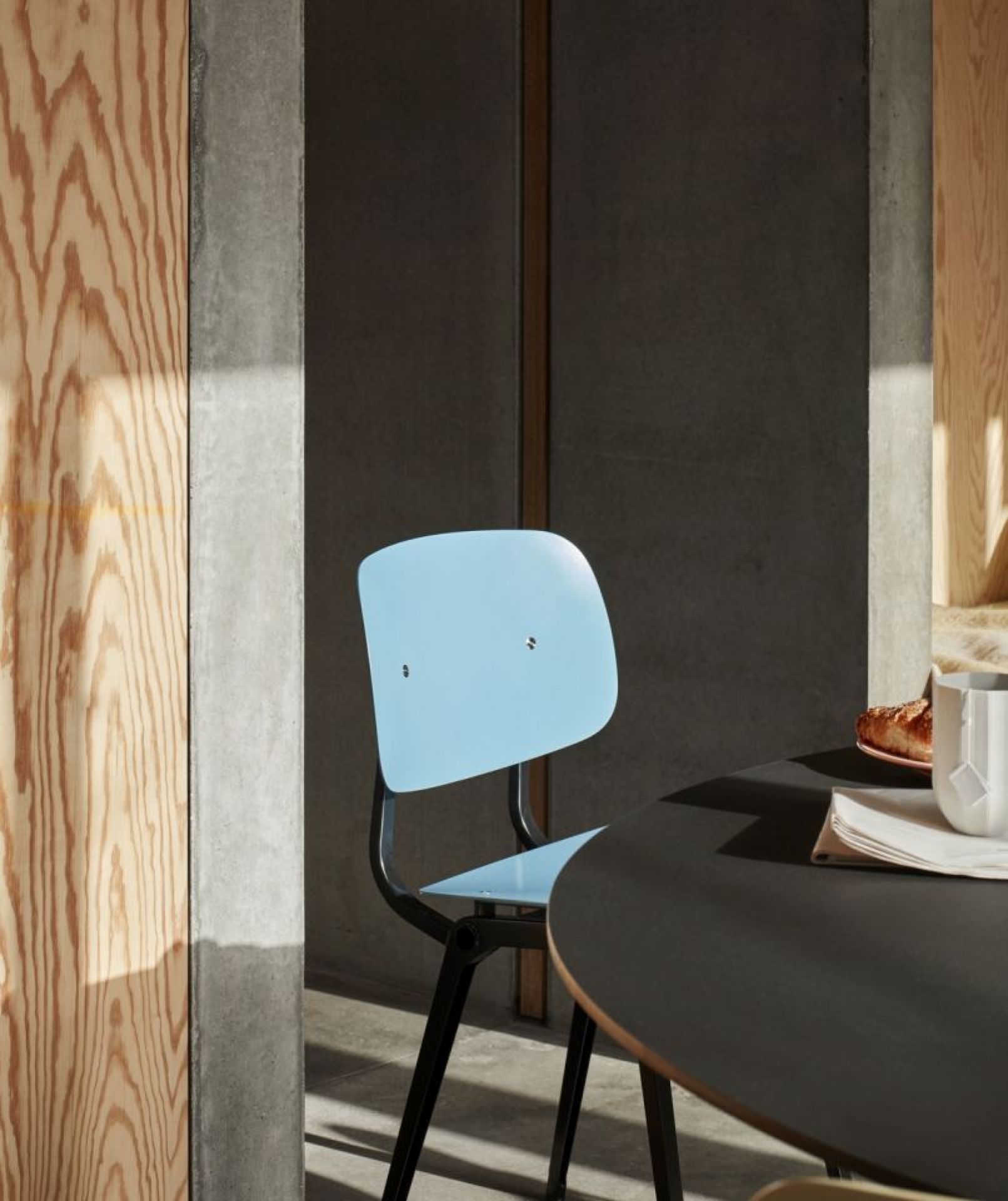 Blauer Hay Revolt Chair Stuhl mit schwarzem Gestell an einem Esstisch in modernem Interieur.