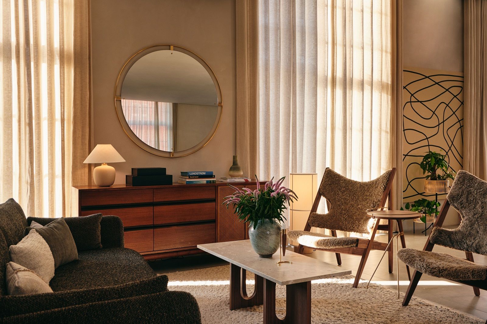 Wohnzimmer mit Audo Copenhagen Gravel Rug Teppich, Sofa, Sessel und Holztisch in warmen Farbtönen.