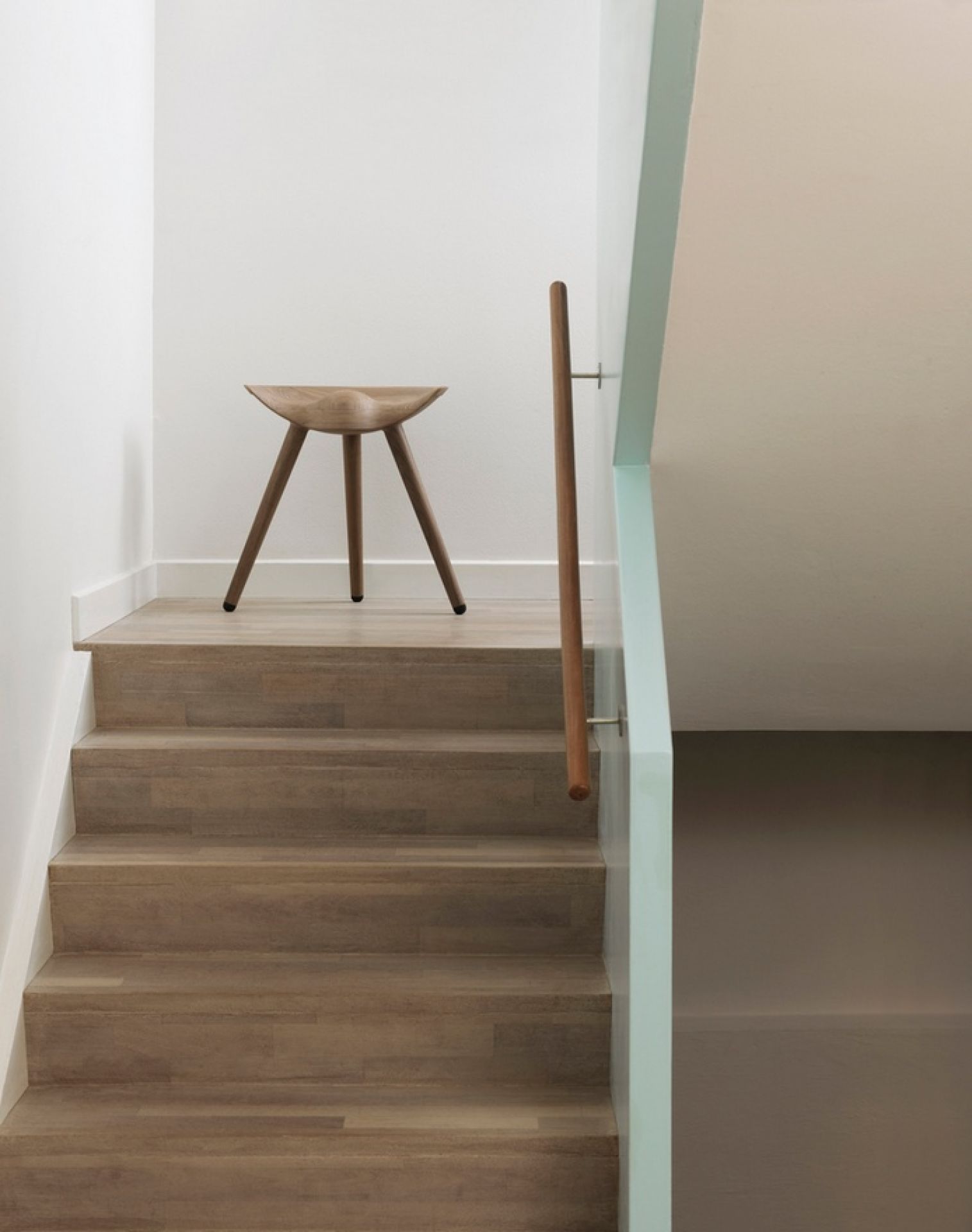ML42 Hocker Audo aus Holz auf einer Treppe, minimalistisches Design für modernes Wohnen.