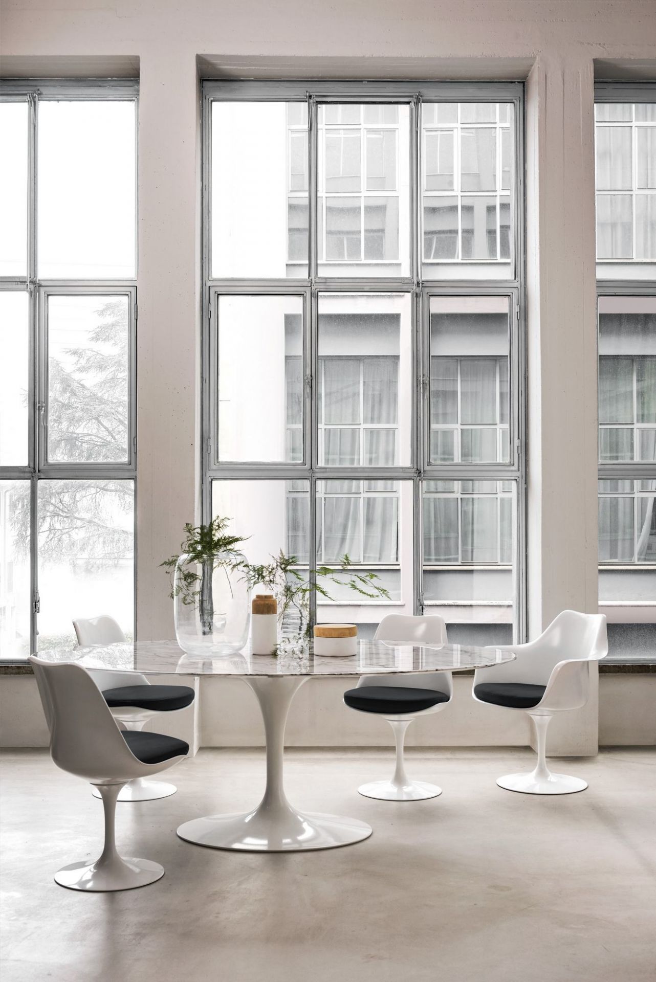 Esszimmer mit Marmortisch und vier weißen Tulip Armlehnstühlen von Knoll International mit schwarzen Sitzkissen.