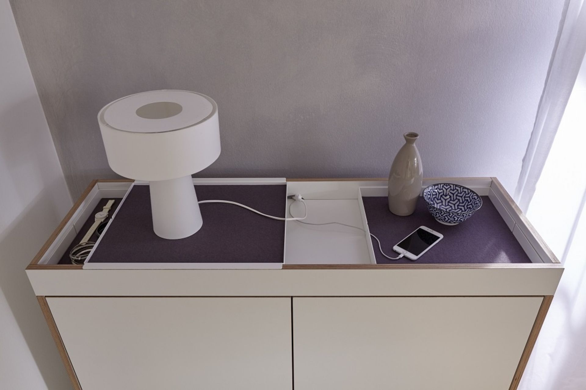 Flai Kommode von Müller Möbelwerkstätten mit Lampe, Schale und Smartphone auf der Ablage.
