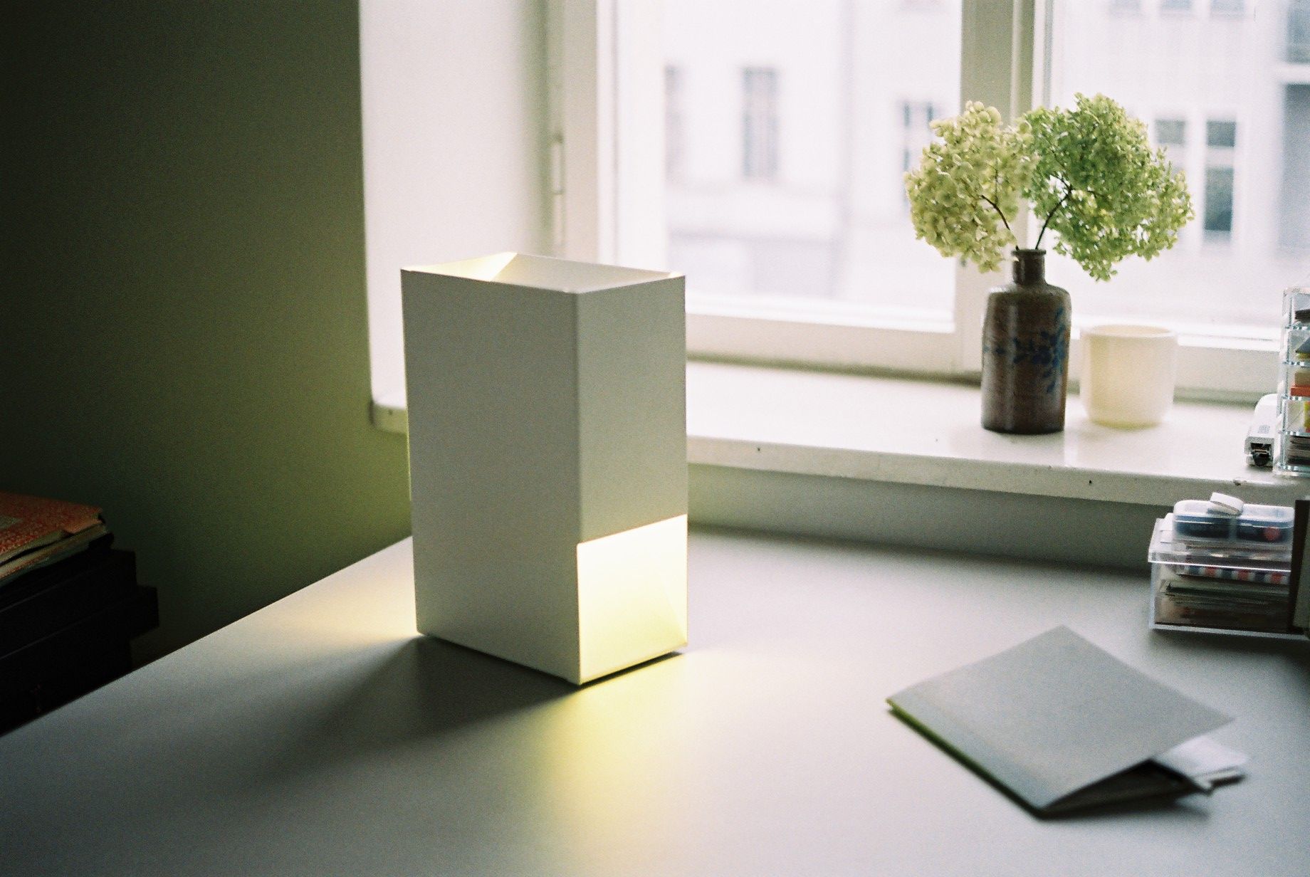 Weiße Linea1 Tischleuchte von Müller Möbelwerkstätten auf einem Schreibtisch, modernes Design mit warmem Licht.