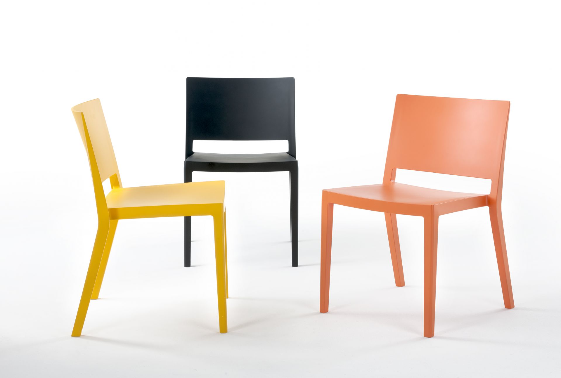 Lizz Stuhlset von Kartell: Drei moderne Kunststoffstühle in Gelb, Schwarz und Orange auf weißem Hintergrund.