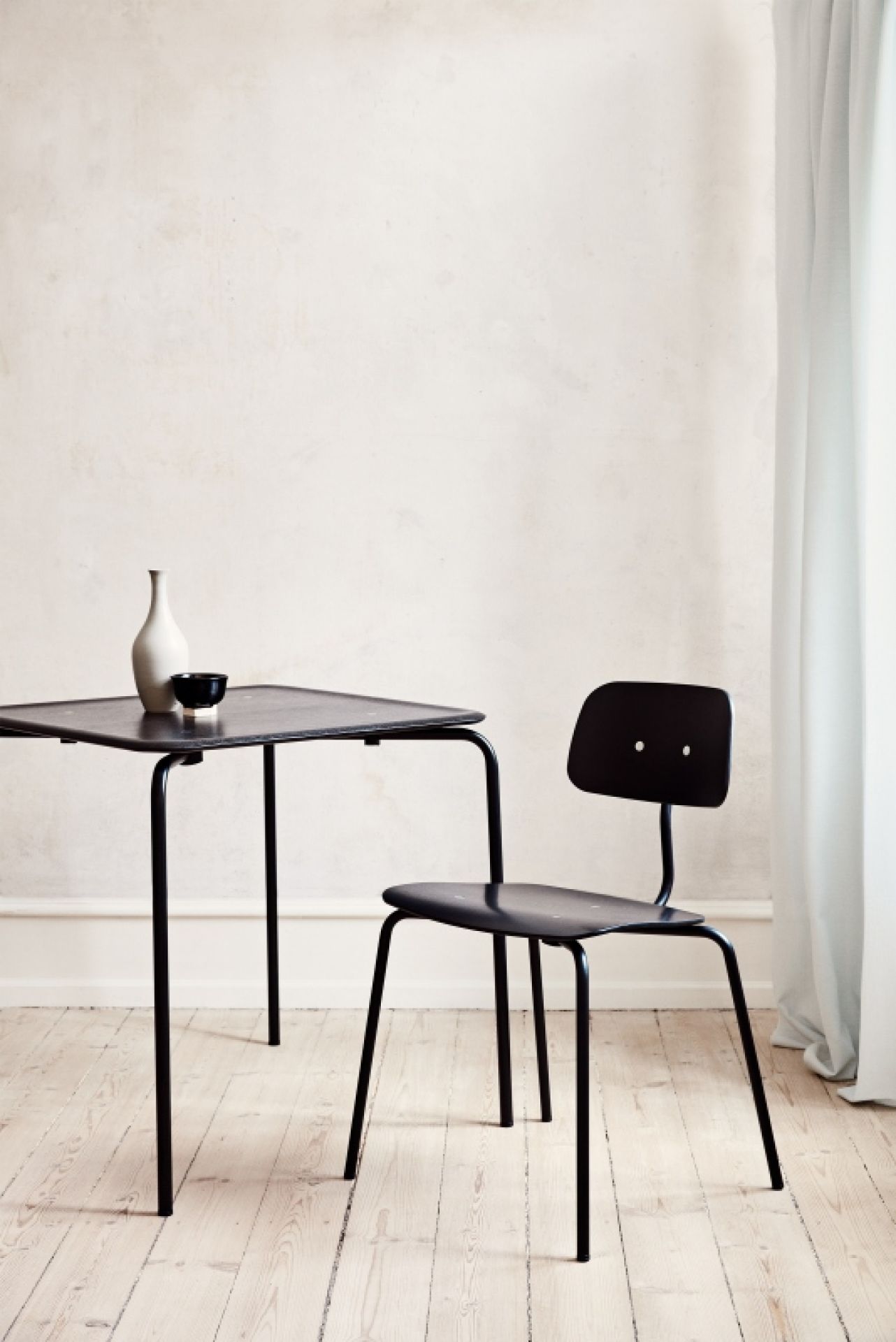 Schwarzer Kevi 2060 Stuhl von Montana mit Tisch und minimalistischer Dekoration vor hellem Hintergrund.