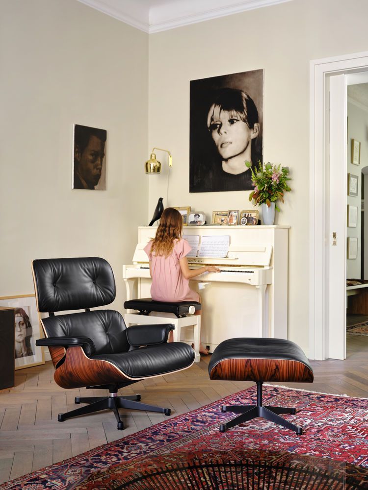 Eames Lounge Chair mit Ottoman in schwarzem Premium Leder und dunklem Holzfurnier in Wohnzimmer.