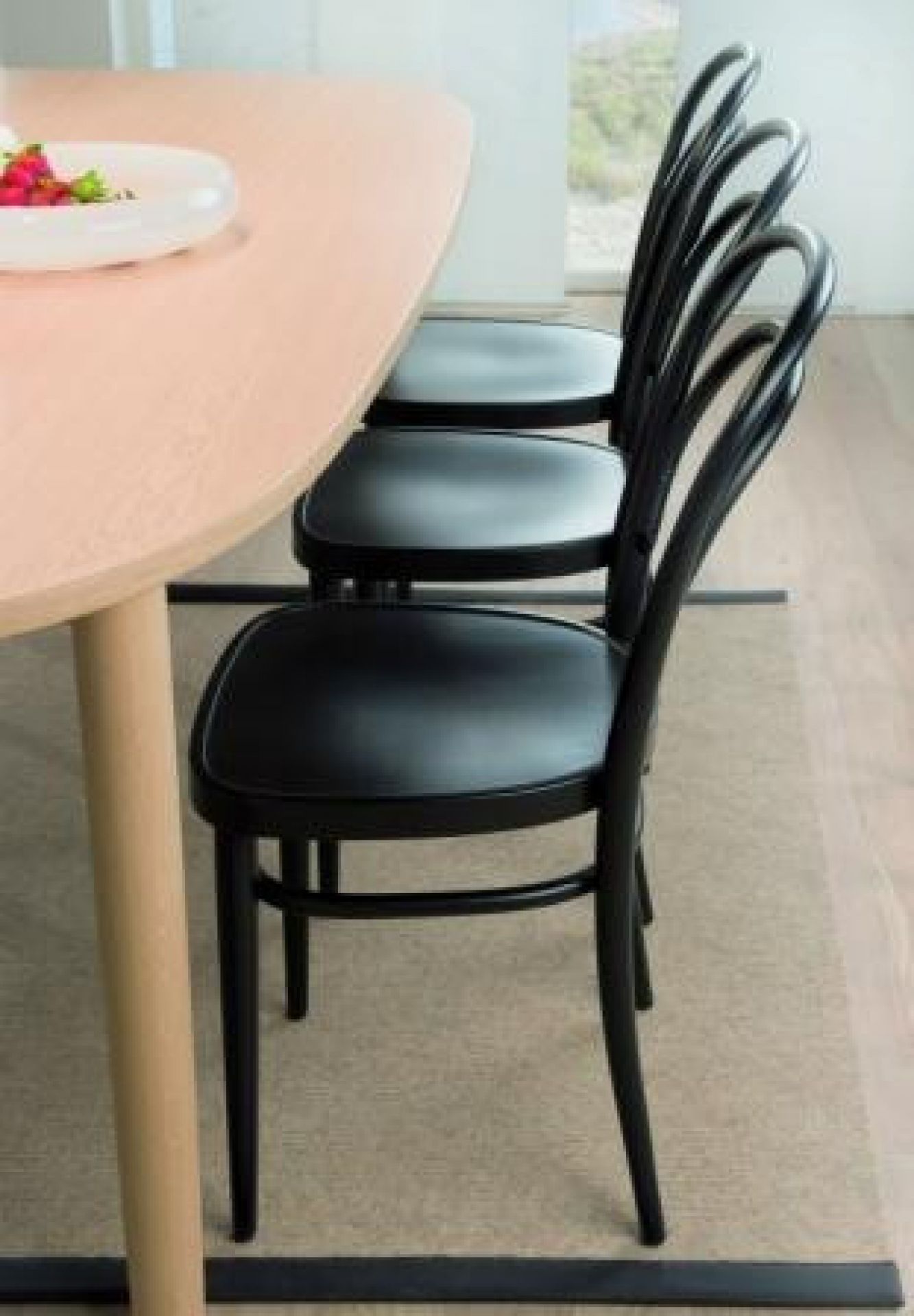 Schwarzer 214 M Bugholzstuhl, ein klassischer Kaffeehausstuhl von Thonet, neben einem Holztisch.