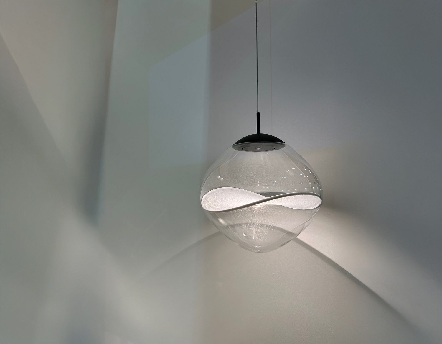 Aether Pendelleuchte von Lumina: Moderne Hängelampe mit transparentem Glasschirm und wellenförmigem, weißem Einsatz.
