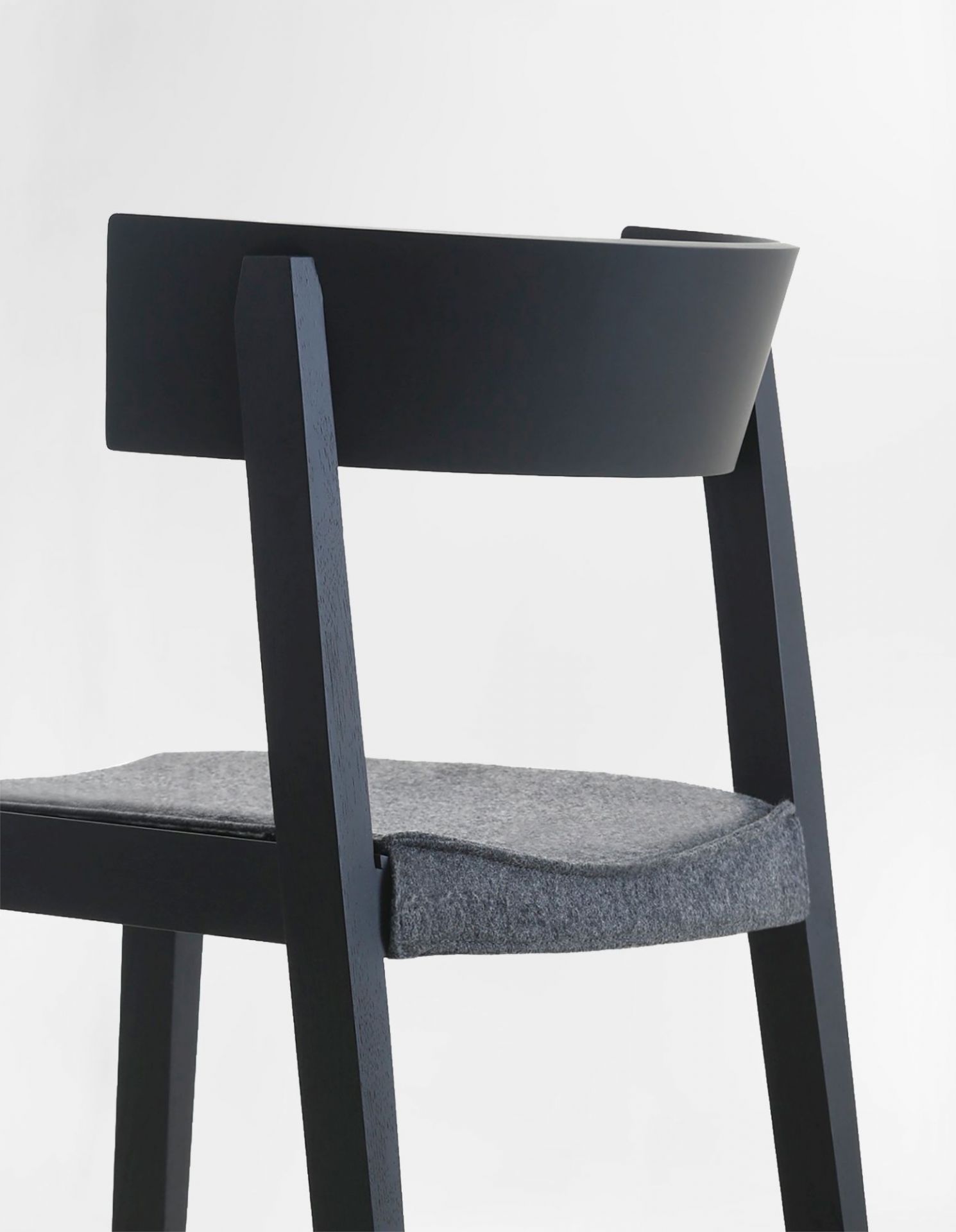 Detailaufnahme des Bik Stuhls von Prostoria: Schwarzes Holzgestell mit grauem, gepolstertem Sitzkissen, ideal für Esszimmer und Wohnbereich.