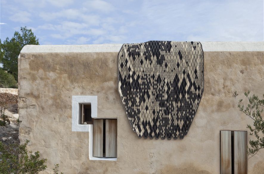 Nanimarquina Losanges Teppich mit Rautenmuster an einer Hauswand drapiert, modernes Design für Wohnräume und Outdoor-Bereiche.
